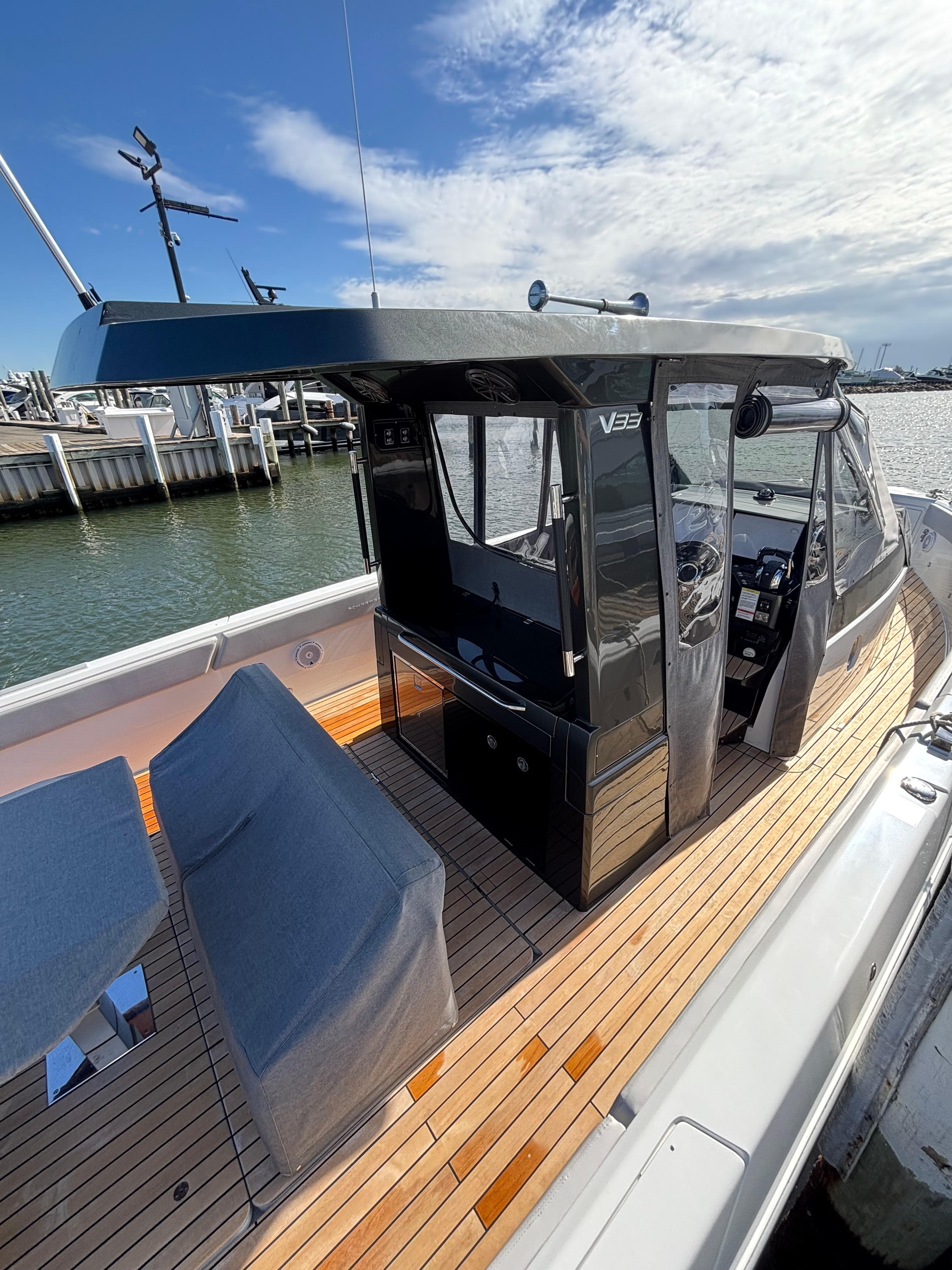 2023 Schaefer V33 boat with sleek design, docked by the water under a clear sky.
