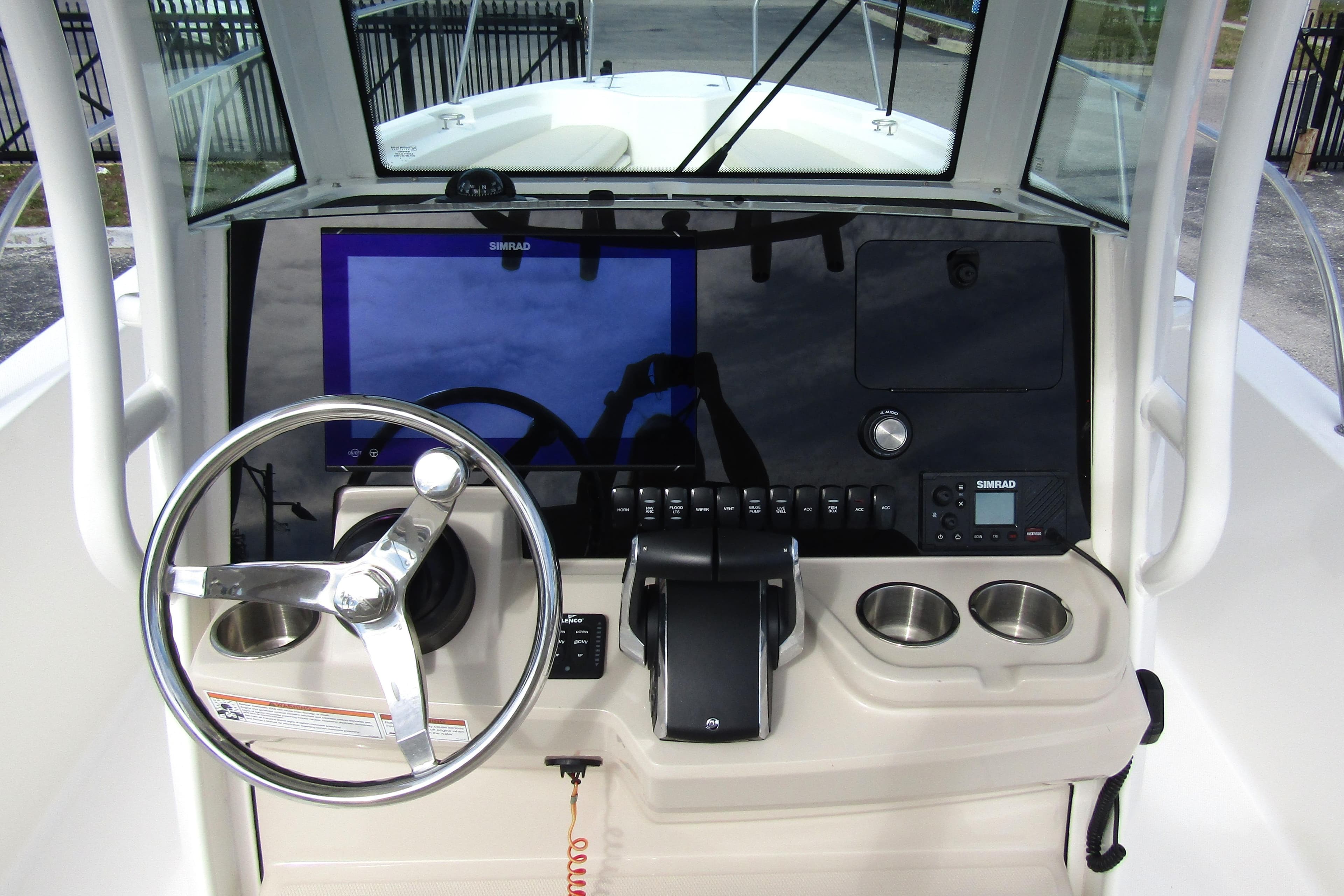 2023 Boston Whaler 280 Dauntless helm with steering wheel, Simrad display, and cup holders.
