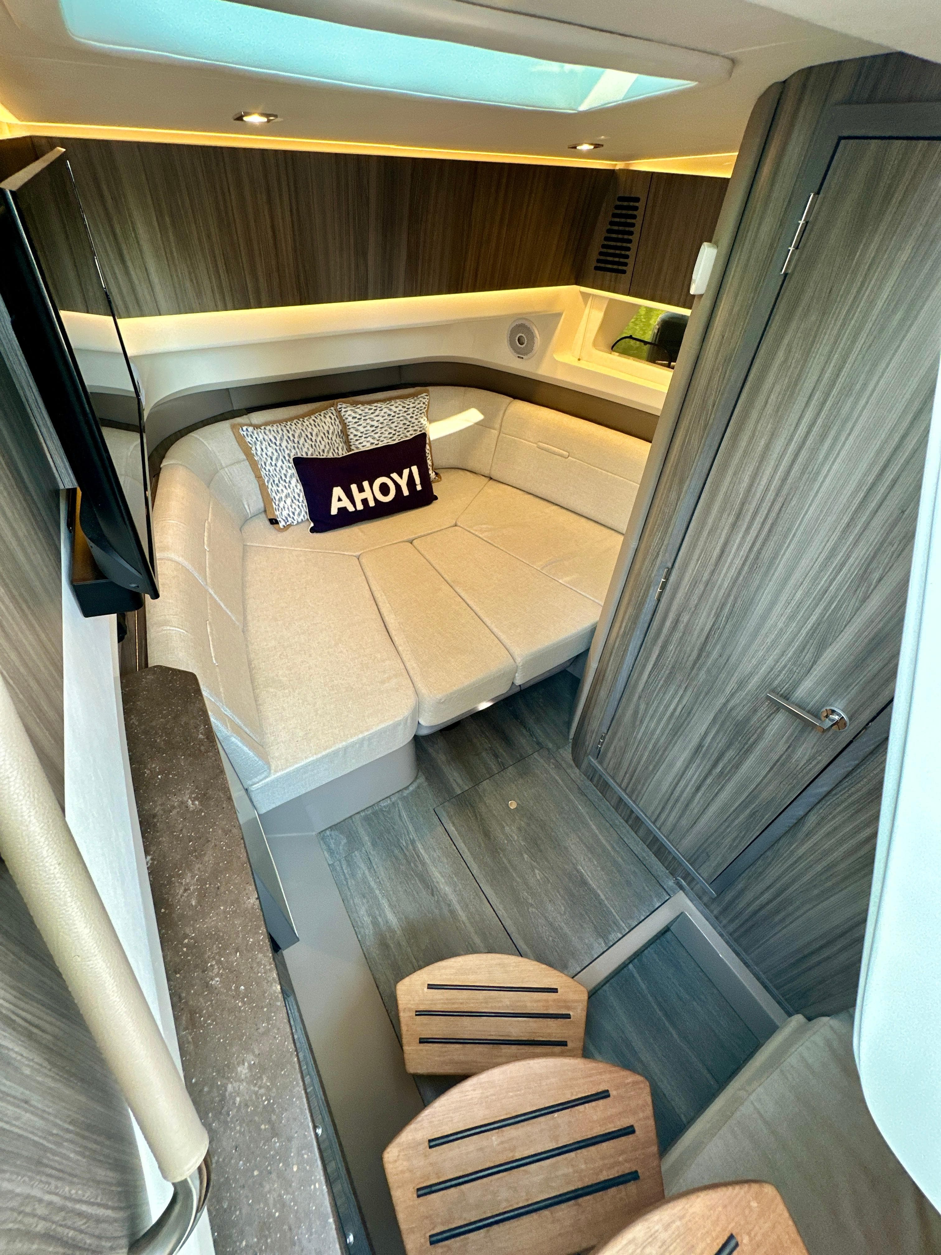 2021 Sea Ray SLX 400 Outboard cabin interior with cozy bed and "Ahoy!" pillow.