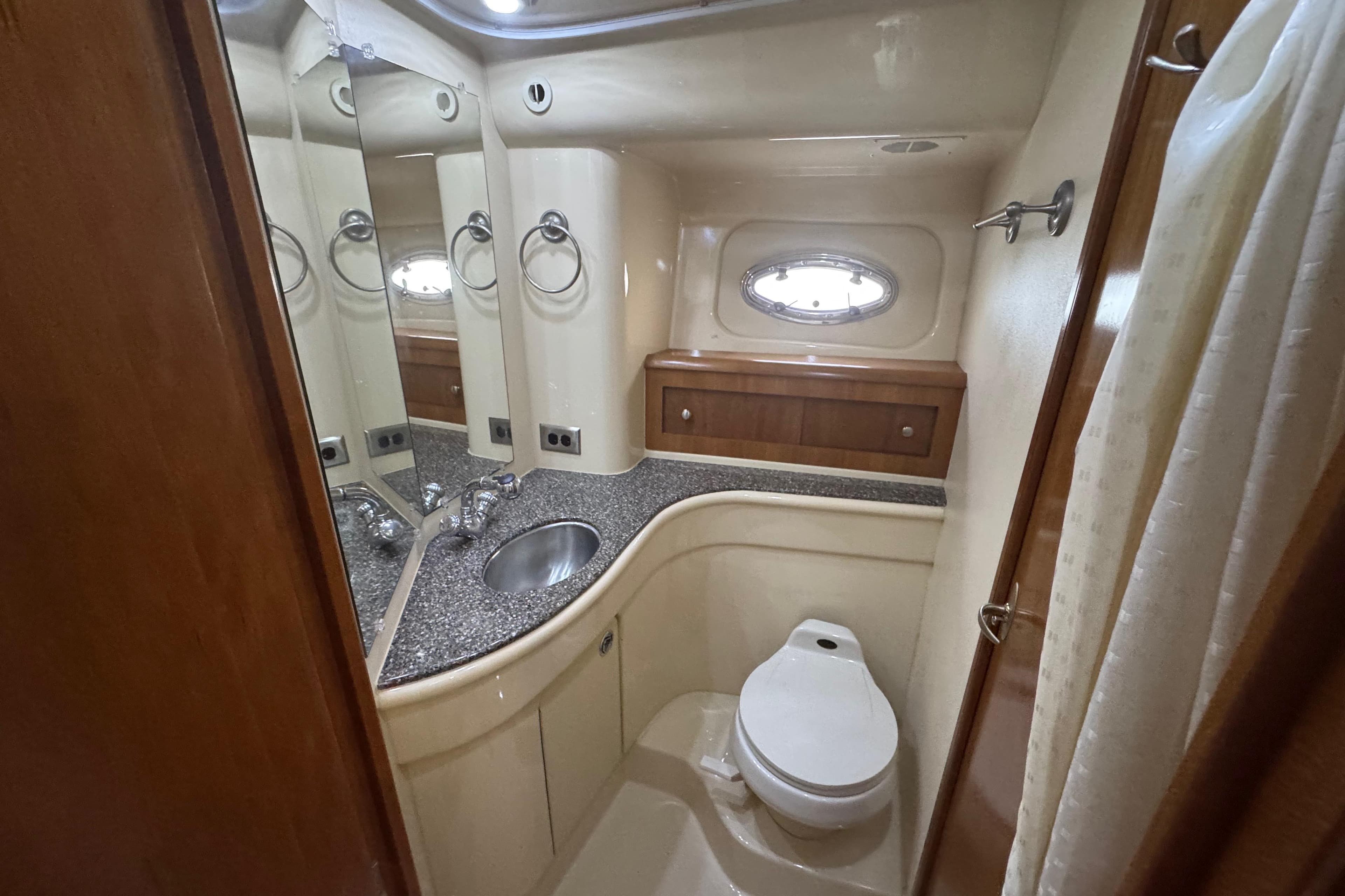 Luxurious bathroom in 2003 Meridian 411 Sedan yacht with modern fixtures and porthole window.