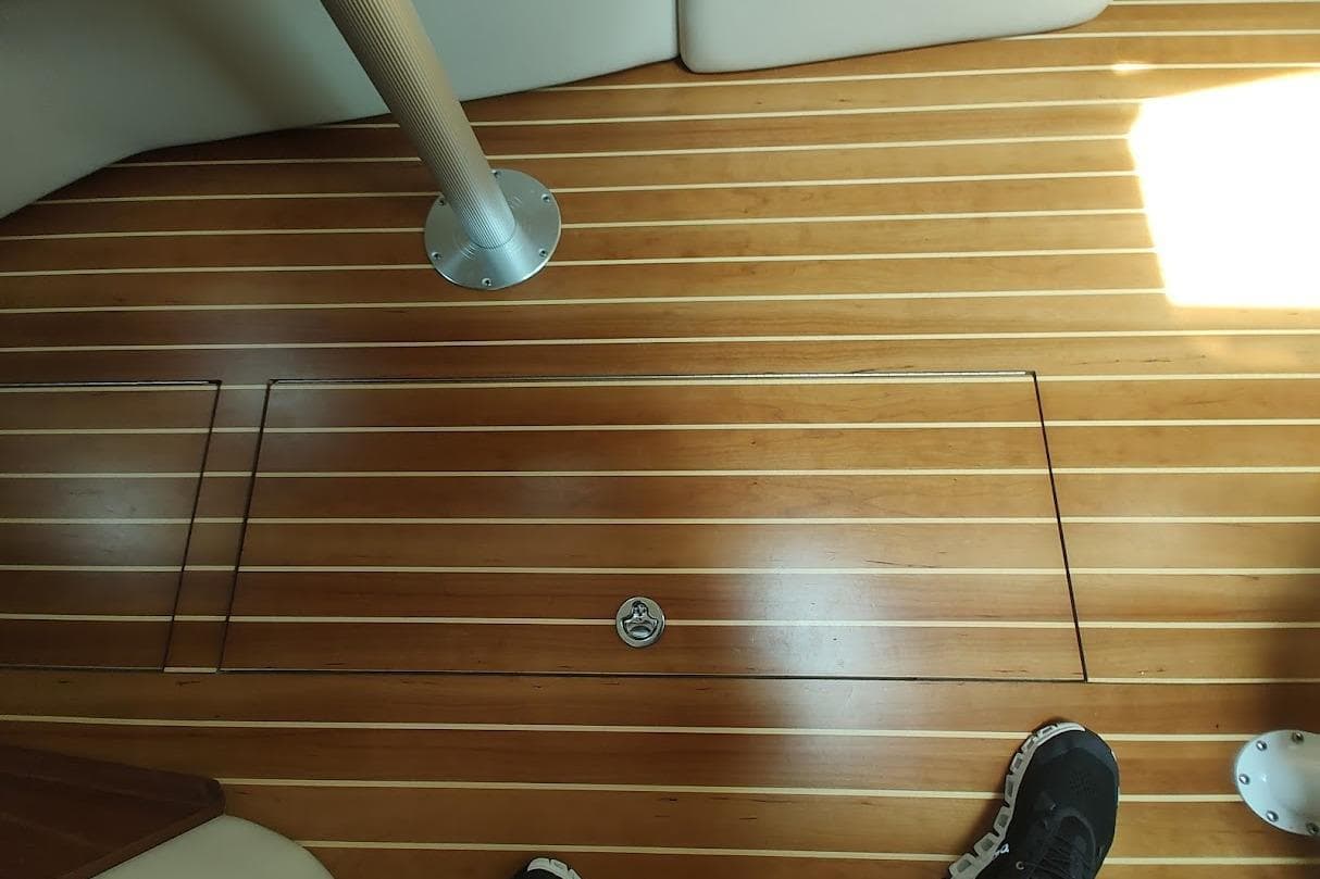 Wooden deck of 2006 Regal Commodore 3560 IO boat with hatch and metal pole.