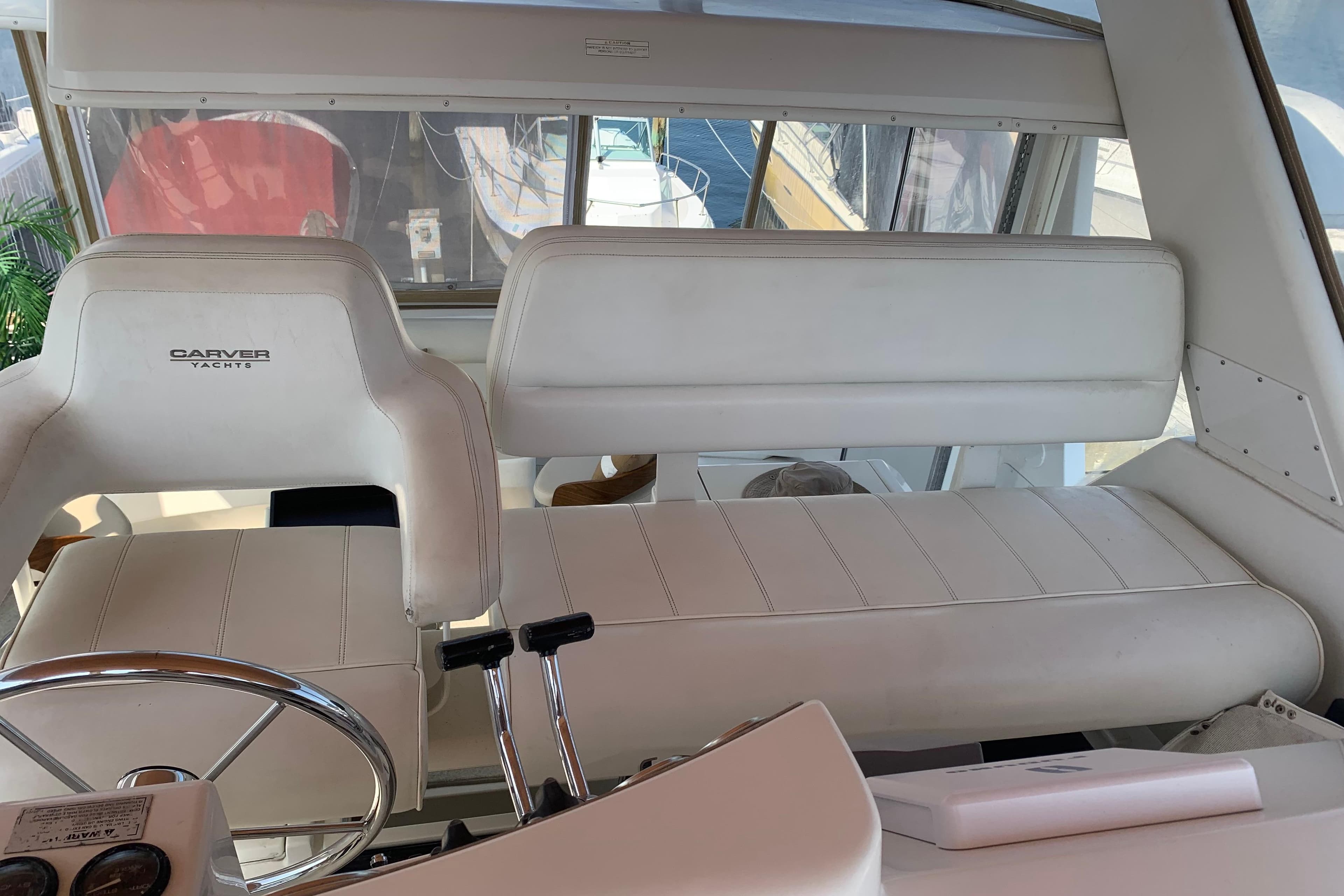 Interior of 2000 Carver 356 Aft Cabin Motor Yacht with white seating and steering wheel.