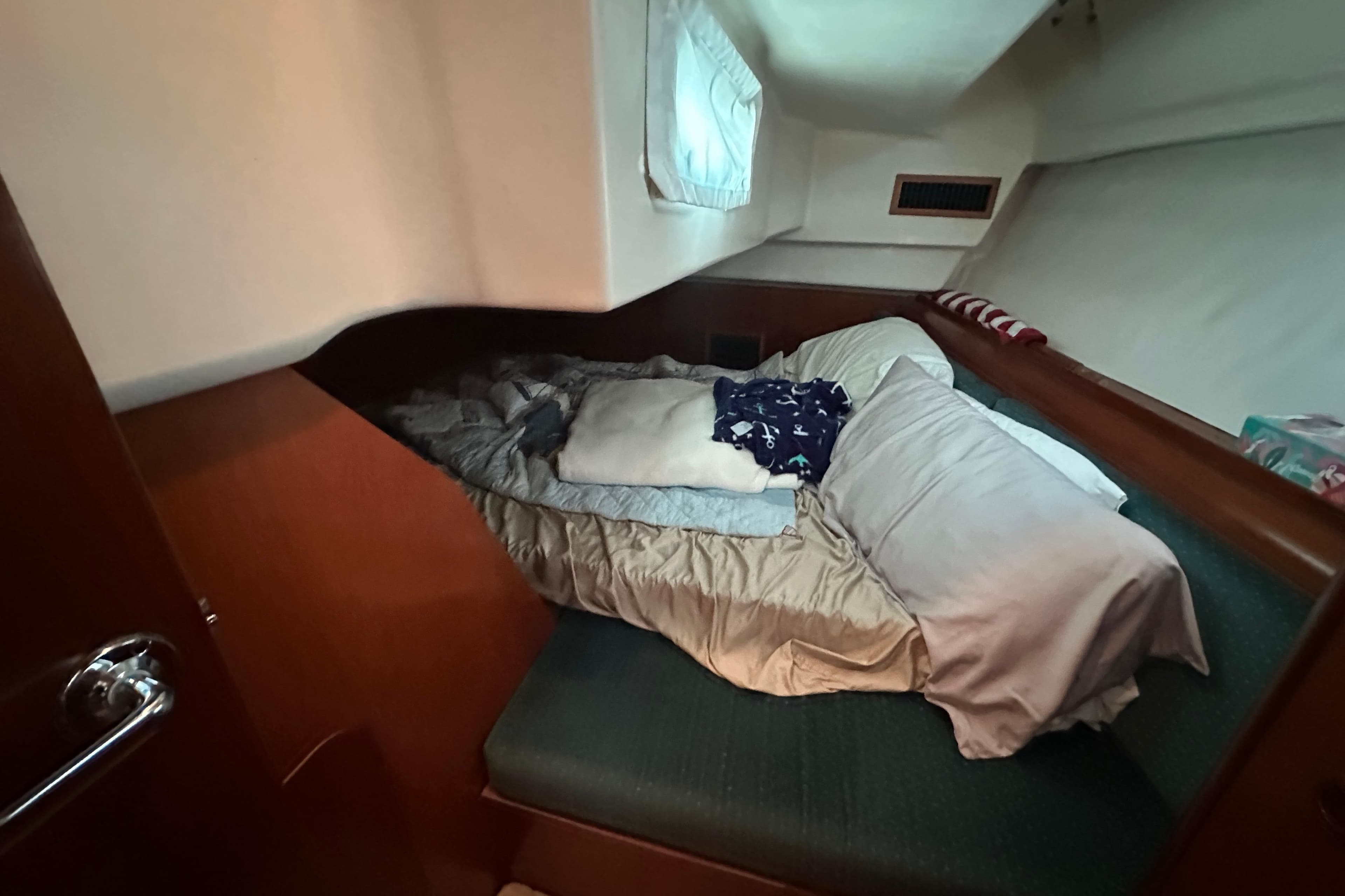 Cozy cabin interior of 2001 Beneteau 381 sailboat with bed and pillows.