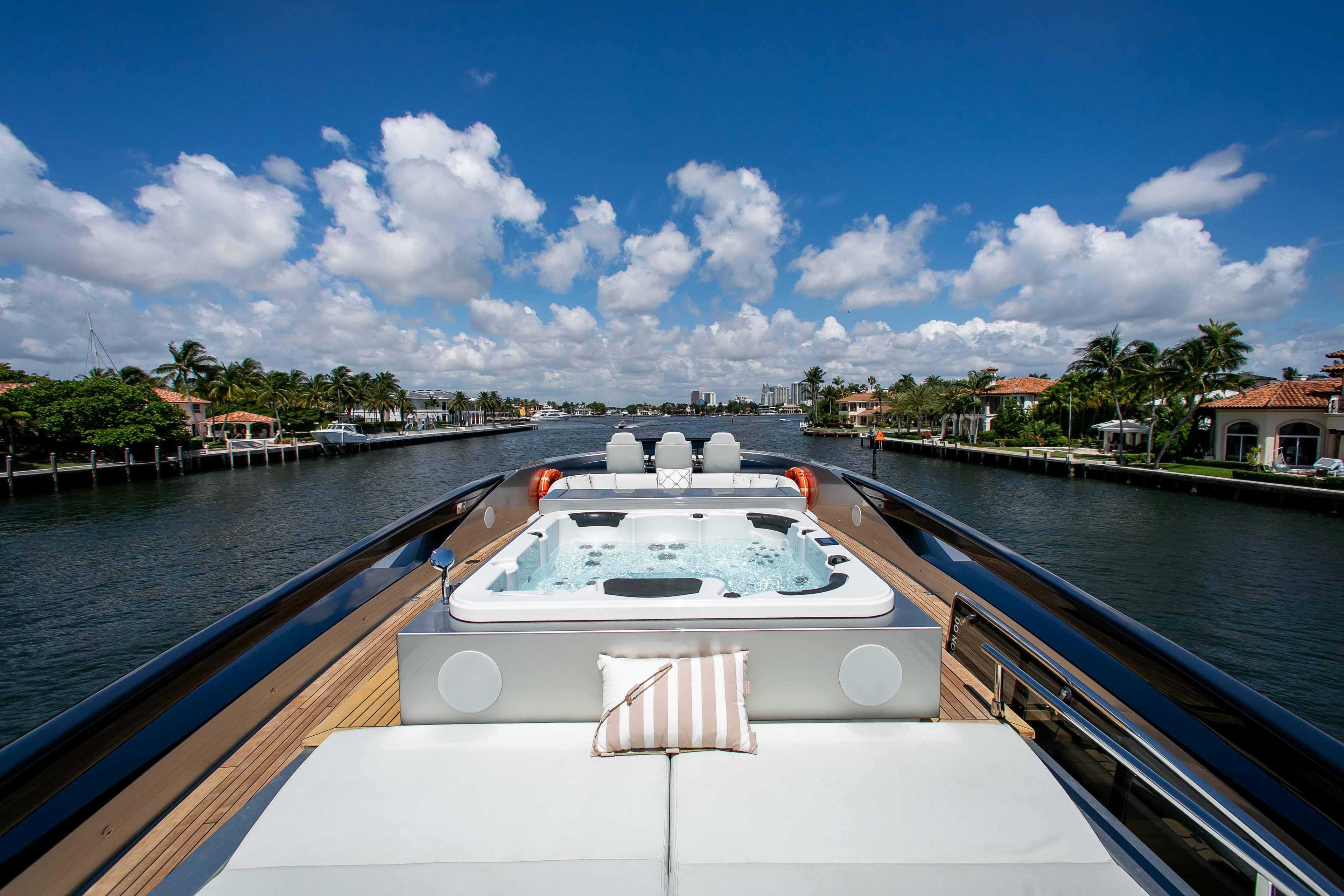 Luxurious 2014 Riva Mythos Motoryacht with jacuzzi, cruising on a scenic waterway under a blue sky.