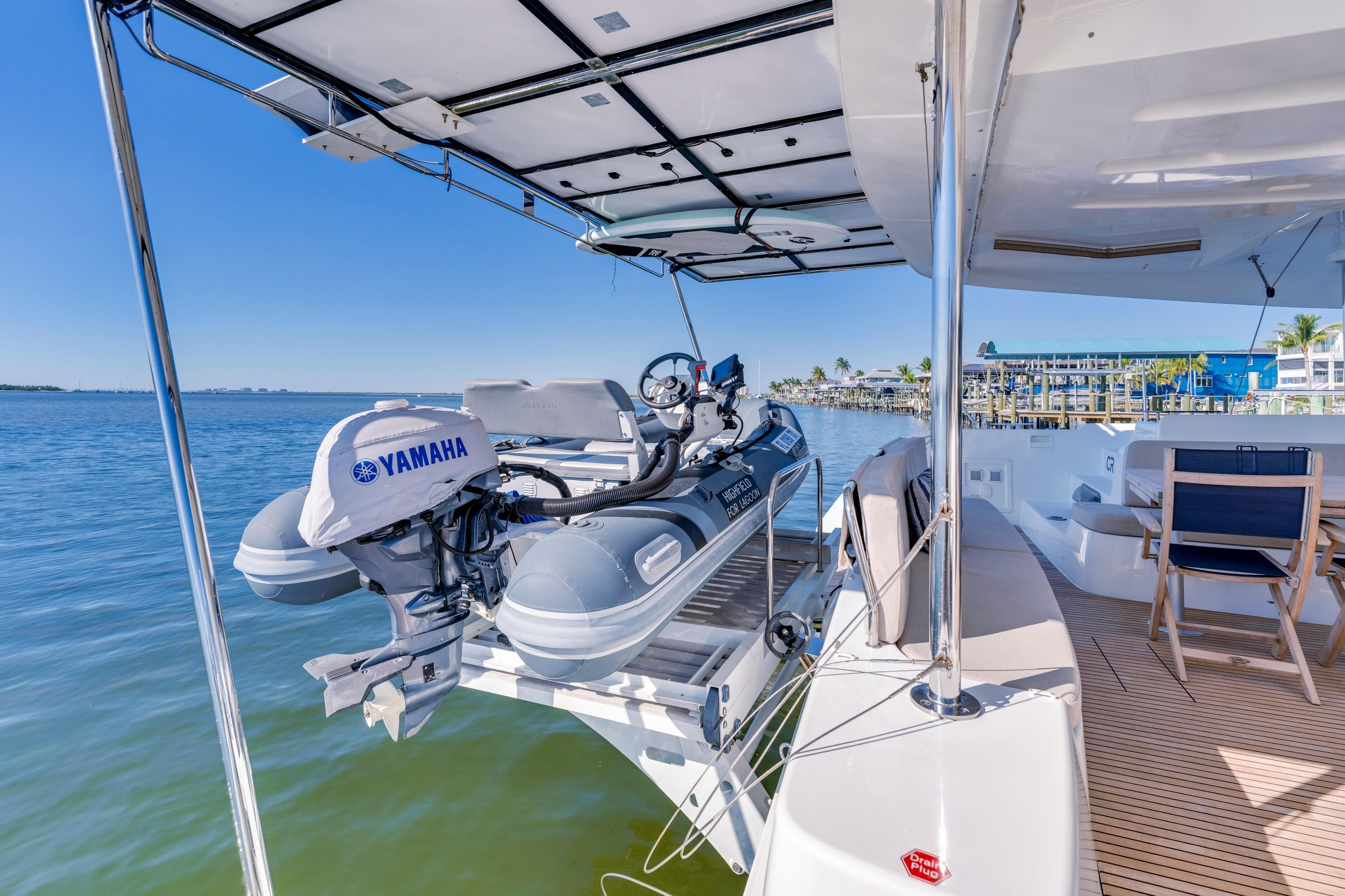 2022 Lagoon 46 yacht with Yamaha motorboat on deck, docked by calm waters.