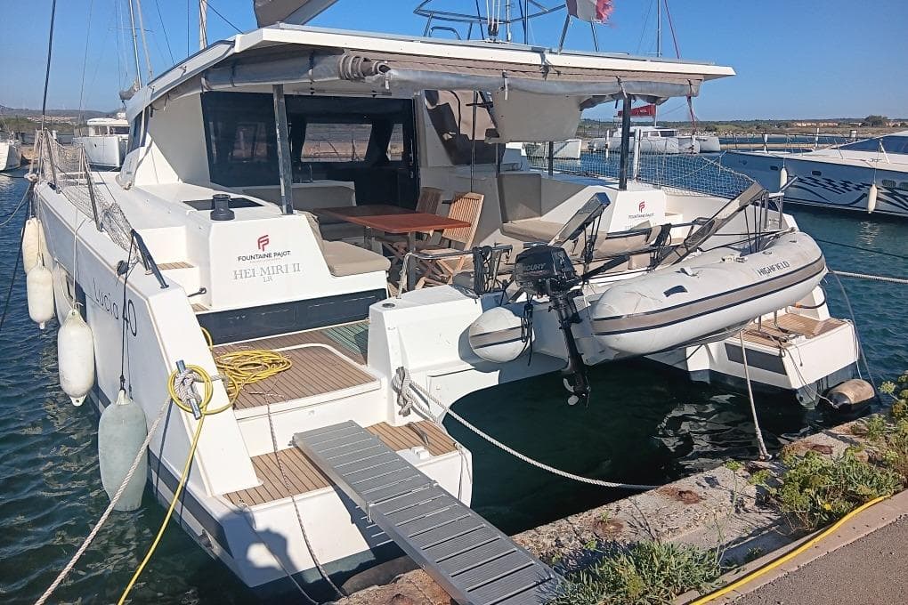 2017 Fountaine Pajot Lucia 40 catamaran docked with dinghy and outdoor seating.