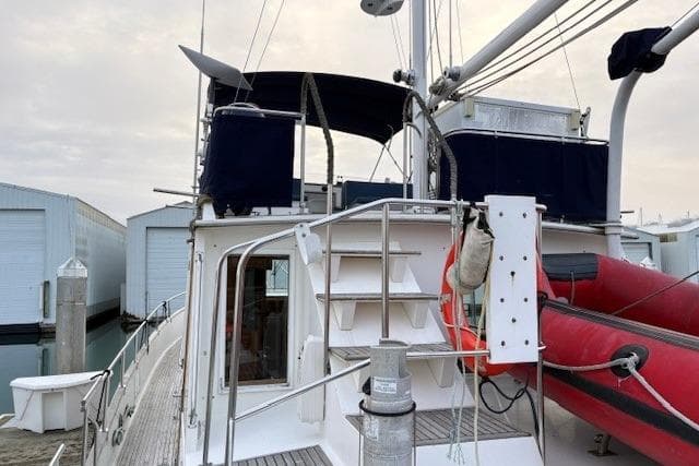 1984 Grand Banks Classic yacht with upper deck, docked near storage units.