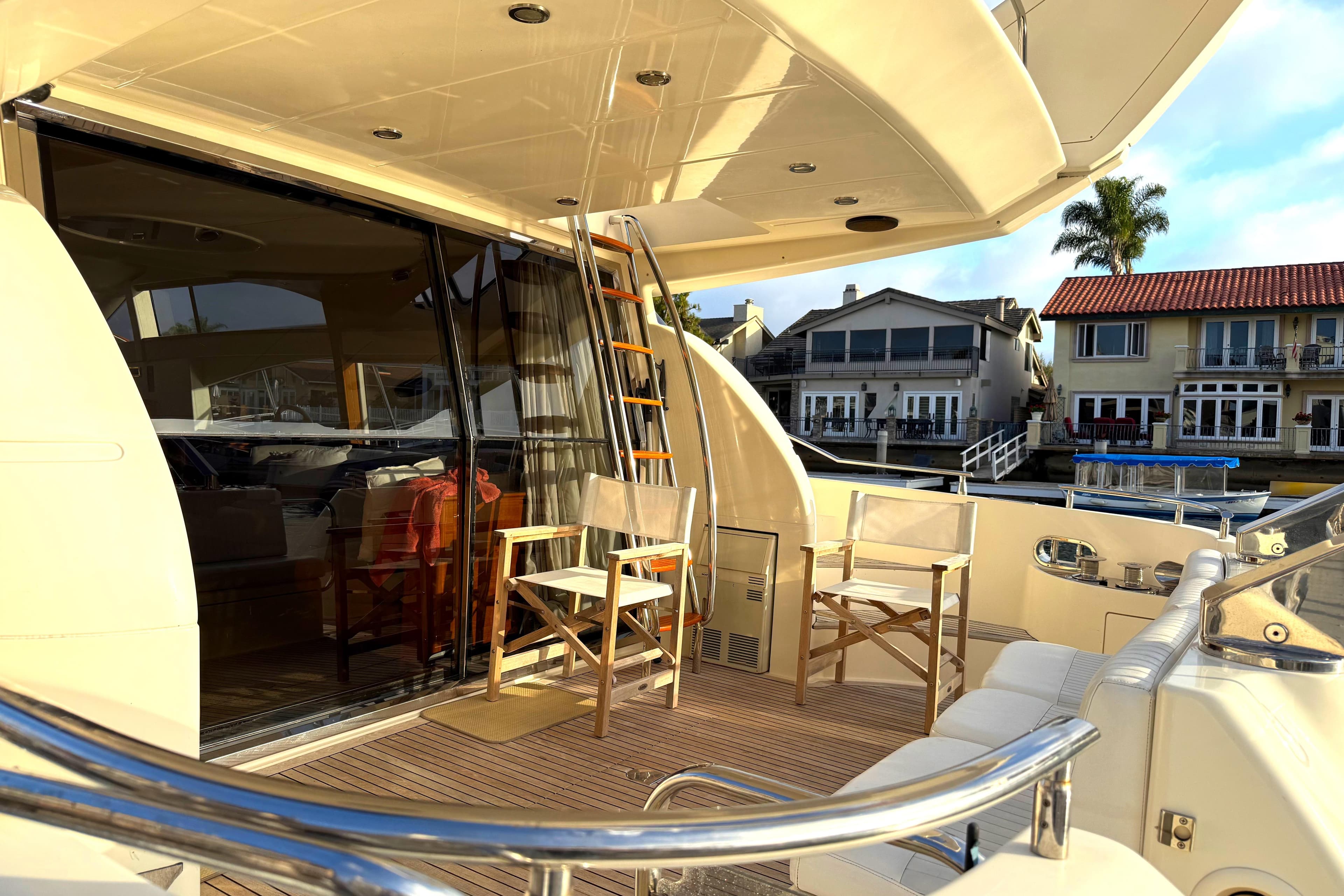 Luxurious 1996 Azimut 54 yacht deck with seating, docked near waterfront homes.