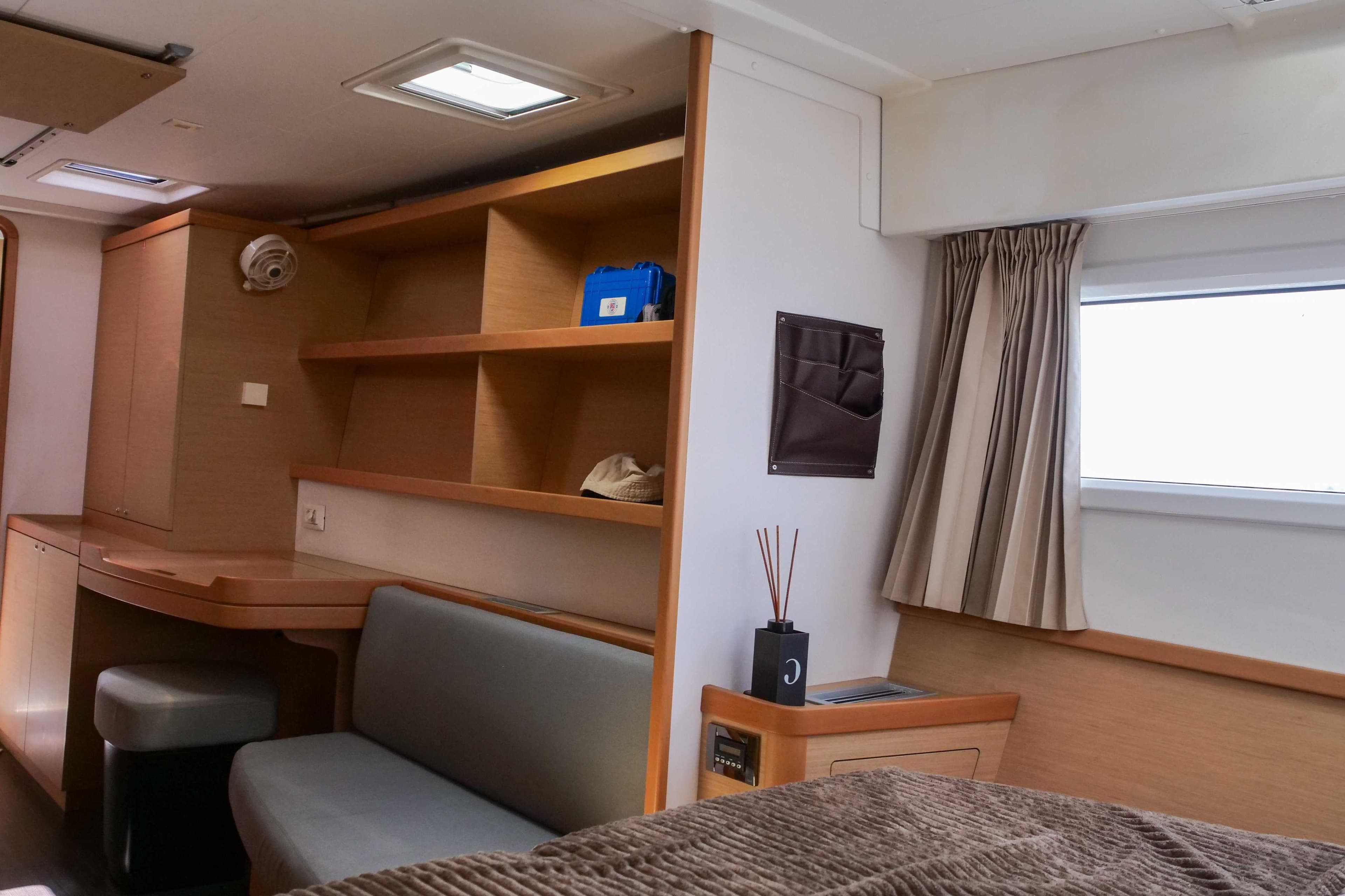 Interior of 2018 Lagoon 42 yacht with cozy seating and wooden shelves.