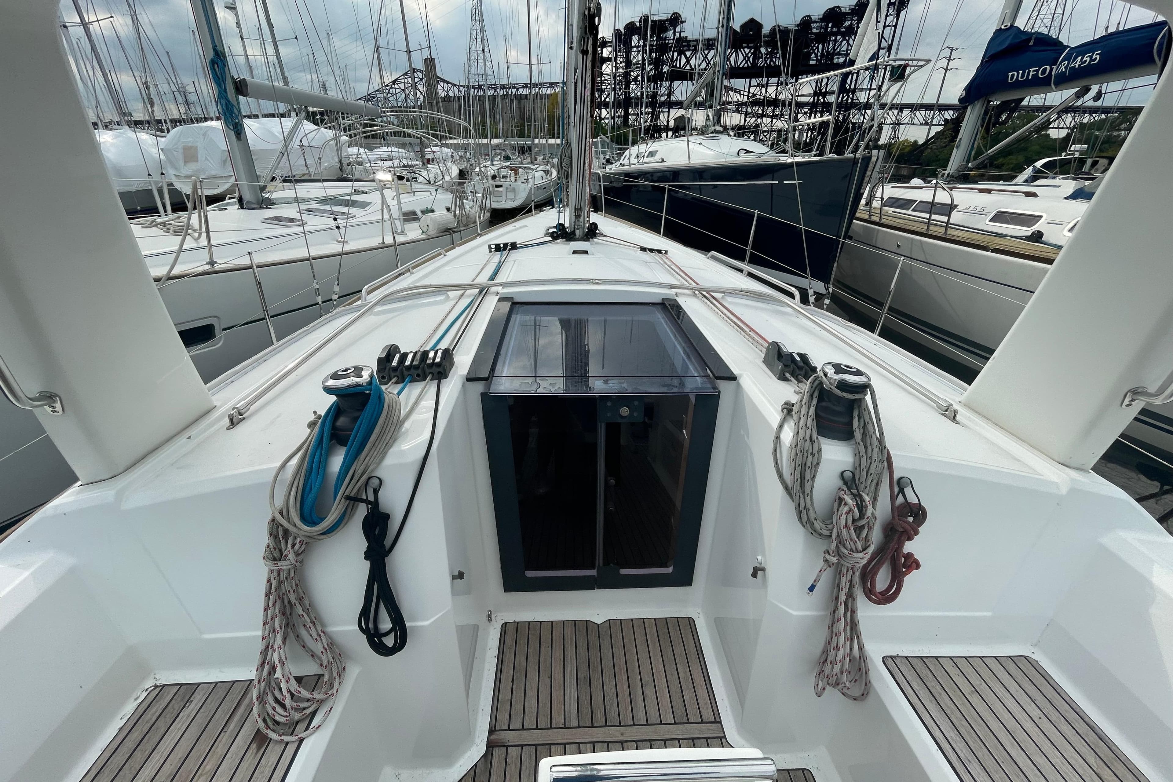 2016 Beneteau Oceanis 38 sailboat deck with ropes and winches in marina setting.