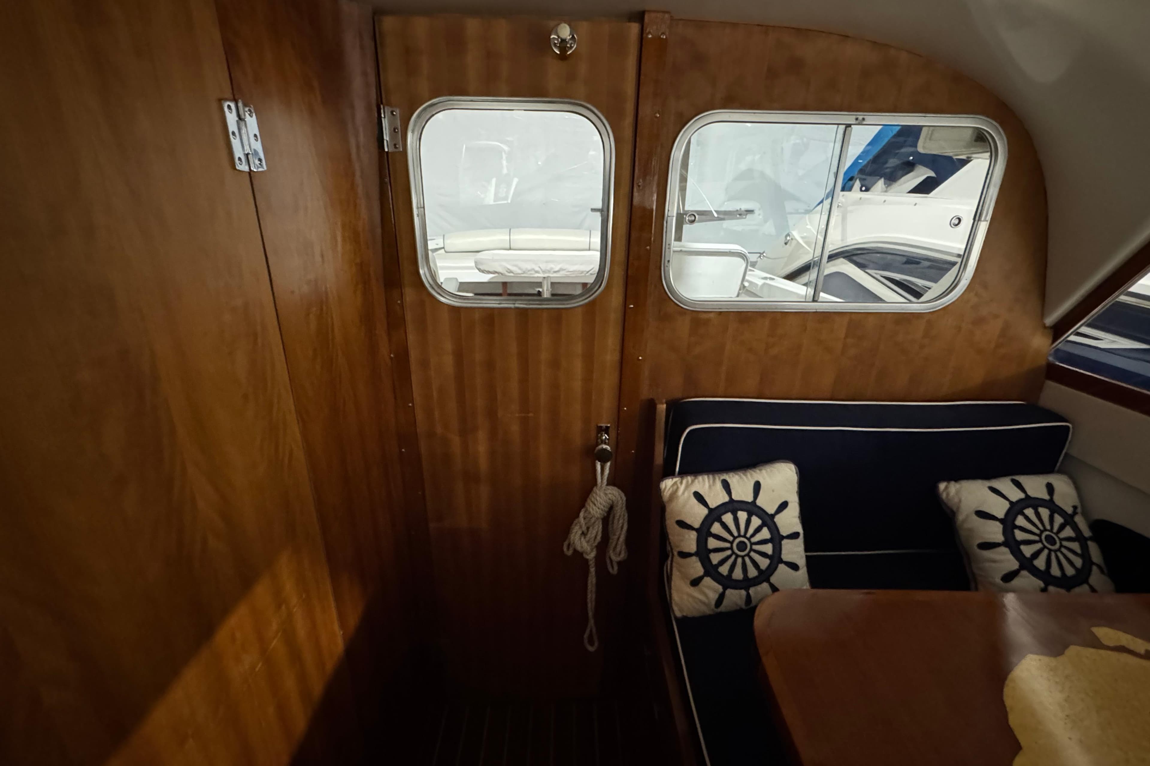 Interior of 1974 Bertram 31 Flybridge Cruiser with nautical-themed cushions and wooden paneling.