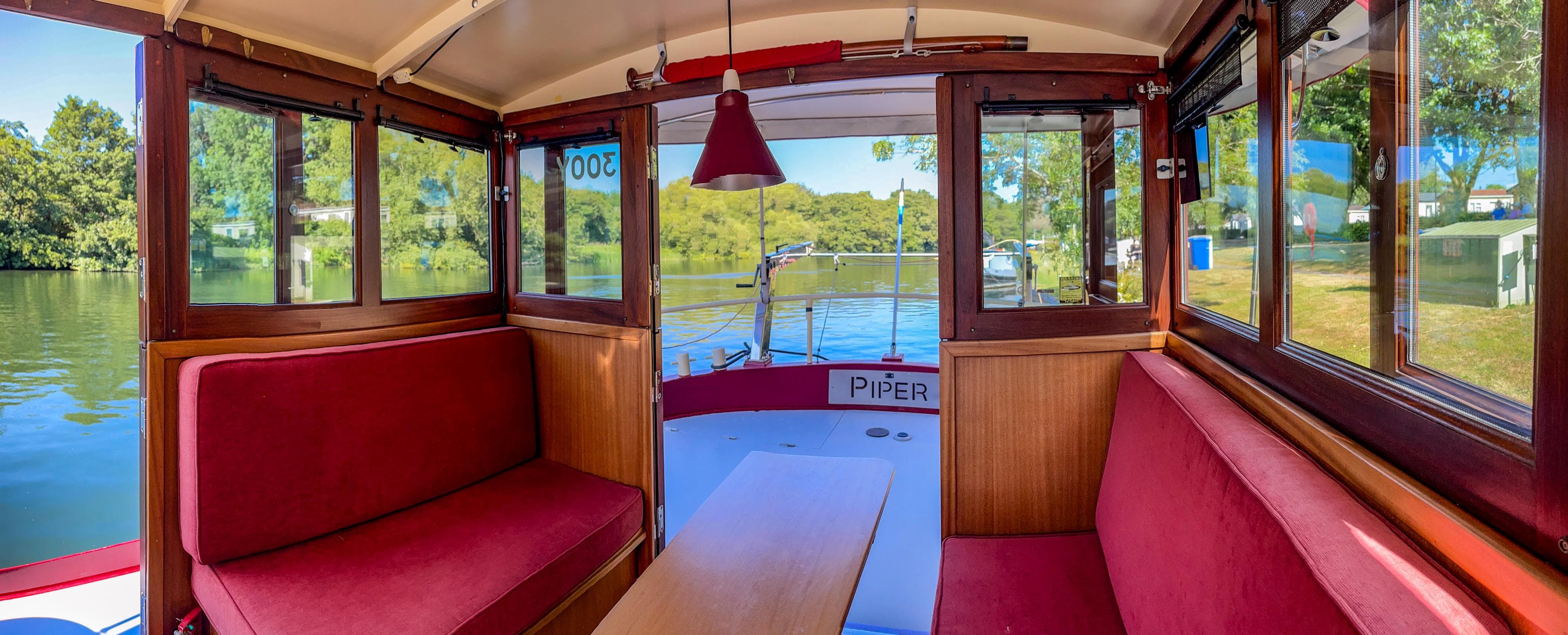 Interior of 2009 Piper 55 boat with red seating and scenic river view.