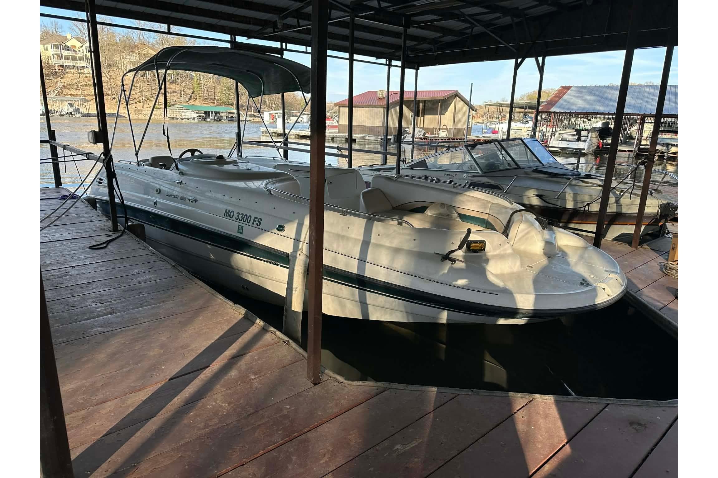 1998 Chaparral Sunesta 252 boat docked in a marina under a covered slip.