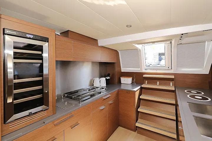 Modern kitchen interior of 2018 Lagoon 620 Esense yacht with wooden cabinetry and appliances.