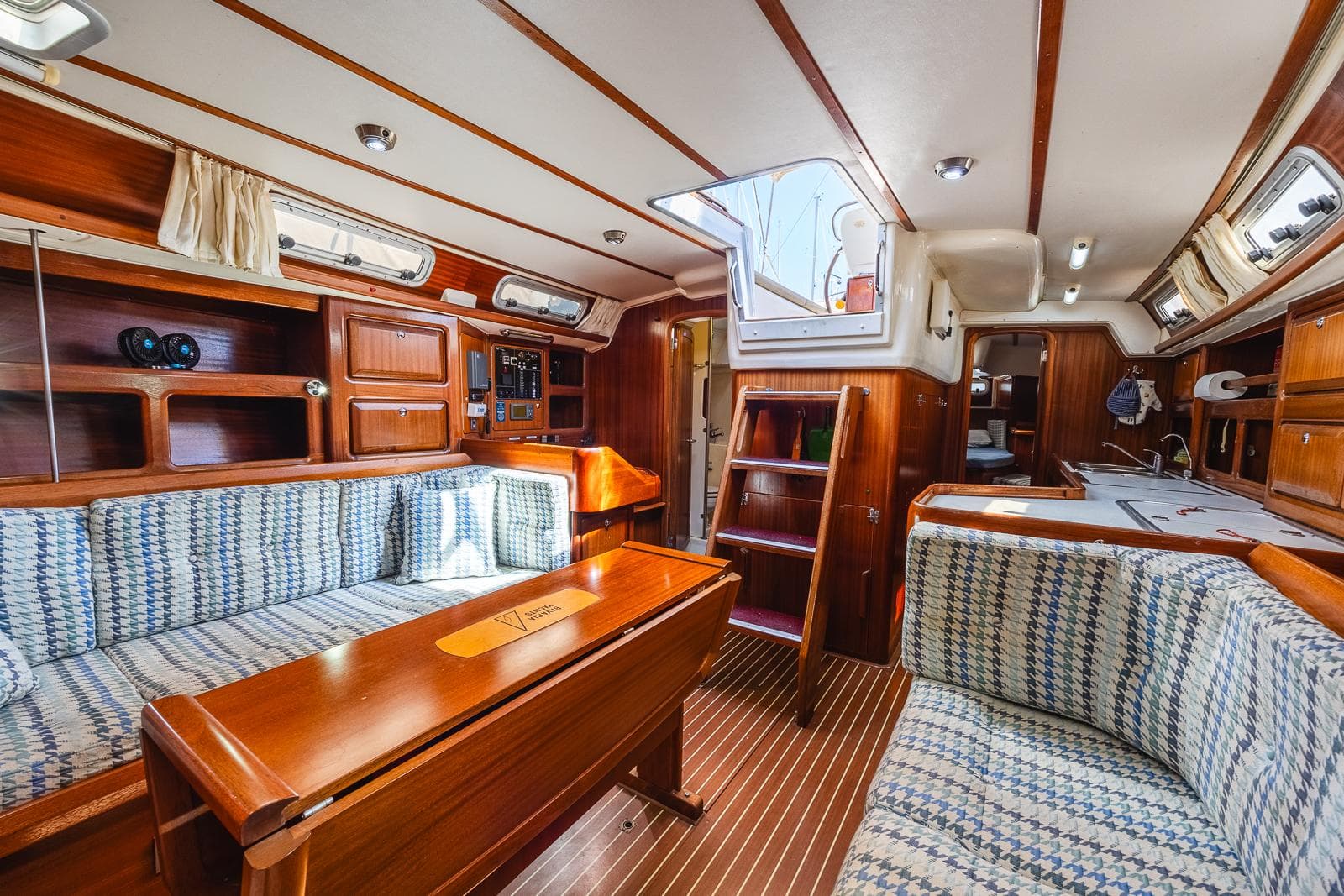 Interior of 1999 Bavaria 42 Ocean yacht with wooden furnishings and cozy seating.