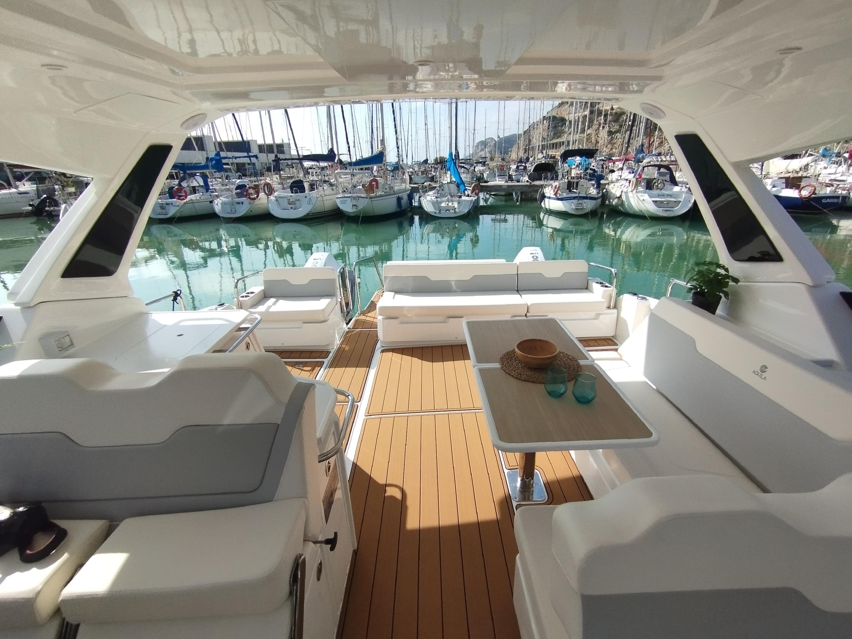 2024 Aquila 36 Sport yacht interior with seating, table, and marina view.