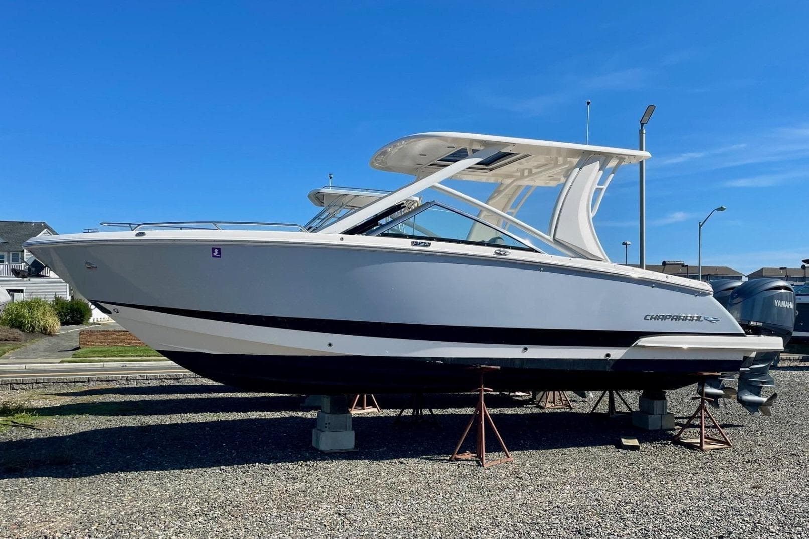 2023 Chaparral 280 OSX boat on display, elevated on stands, under clear blue sky.