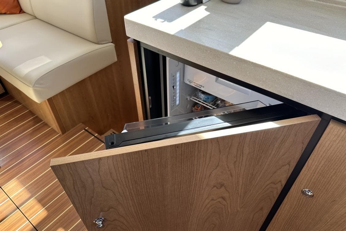 2026 Linssen Grand Sturdy 550 Variotop yacht interior with open fridge and wooden cabinetry.