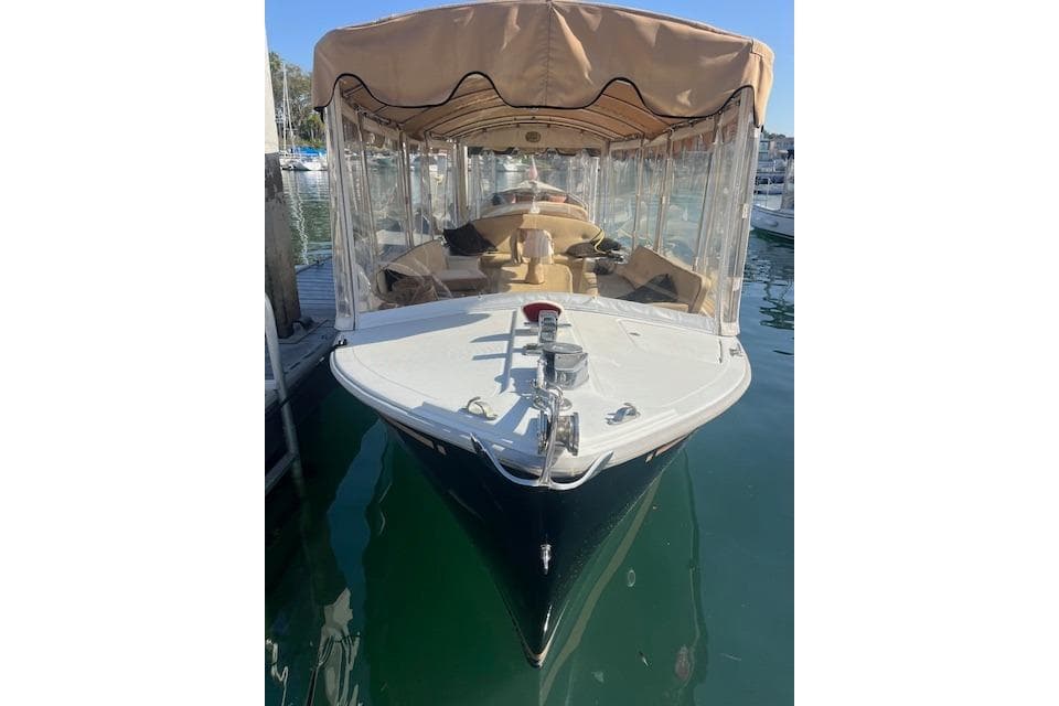 2002 Duffy Classic 21 boat docked with tan canopy and clear side panels.