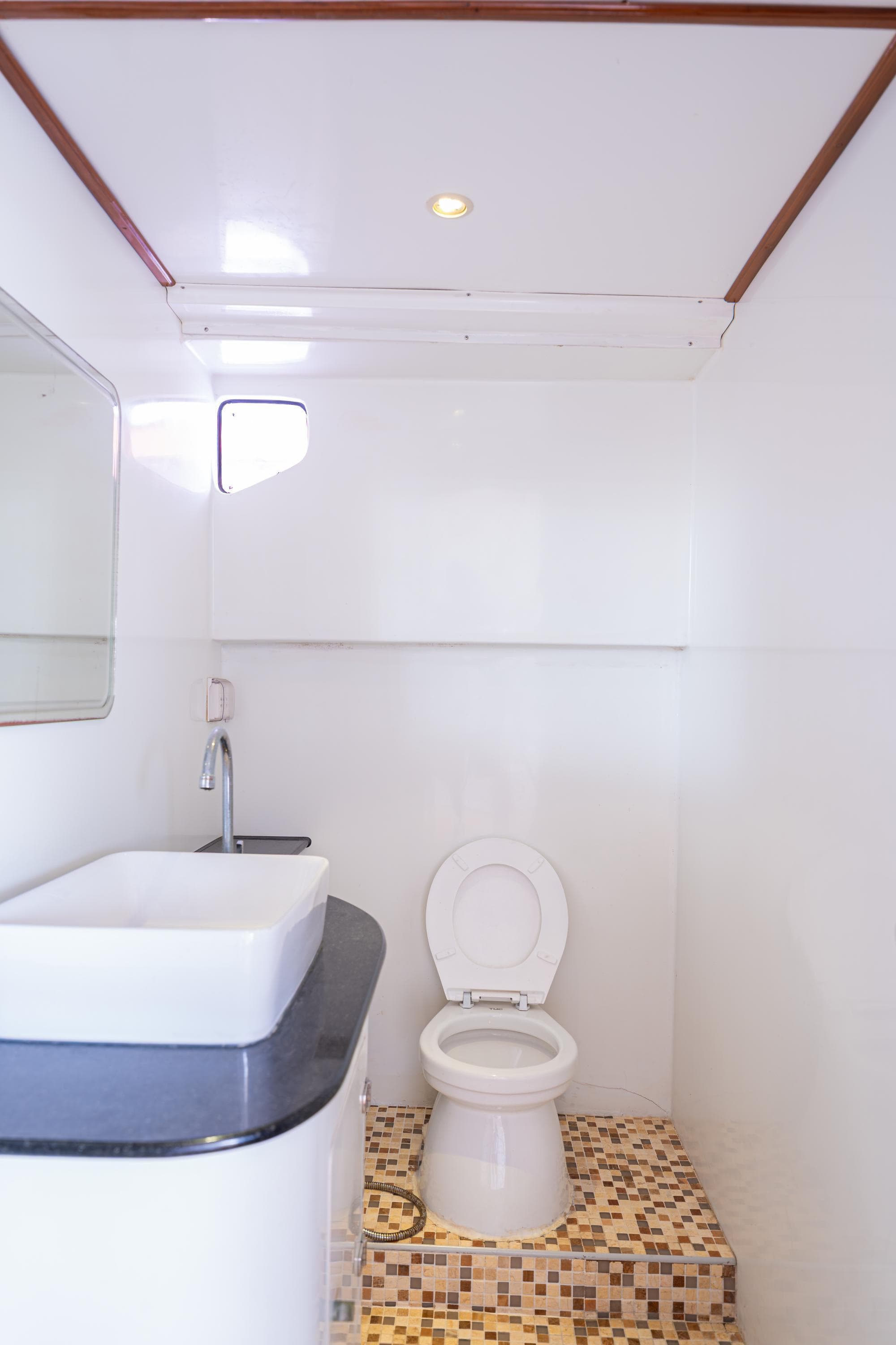 Modern bathroom with white fixtures, mosaic tile floor, and sleek sink in a 2023 Custom Courage 82.