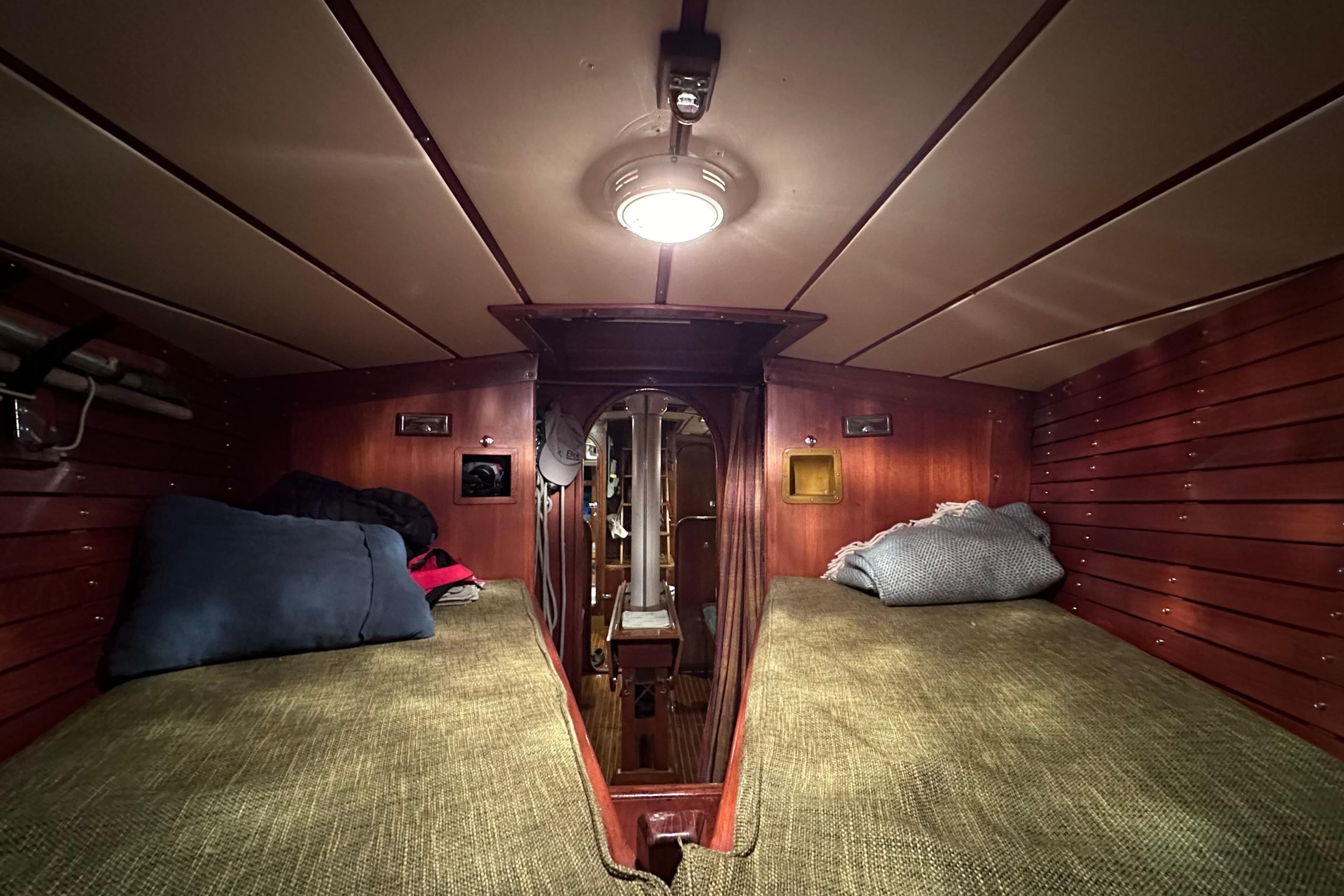 Cozy cabin interior of 1974 Nautor Swan 41 sailboat with wooden paneling and bedding.
