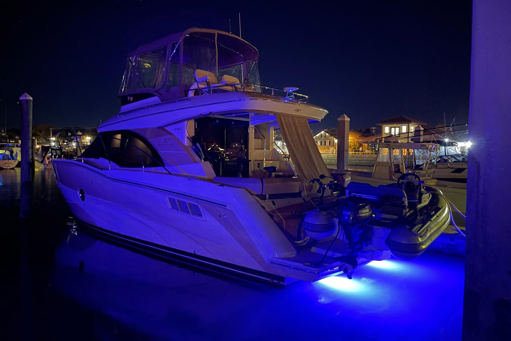 2013 Carver C34 yacht docked at night with blue underwater lights.