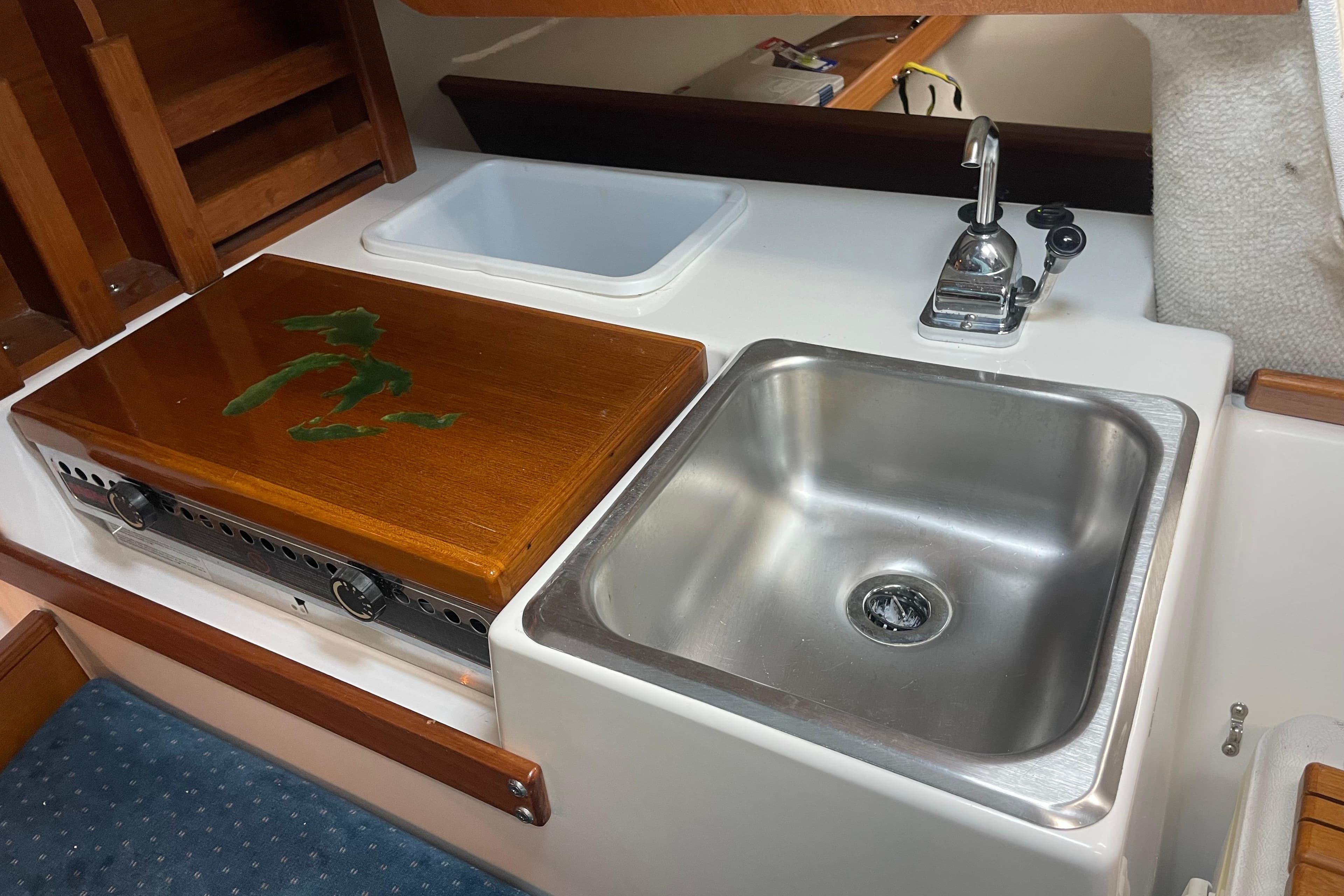 Compact kitchen area in a 2001 Precision 23 boat, featuring a sink and stove.