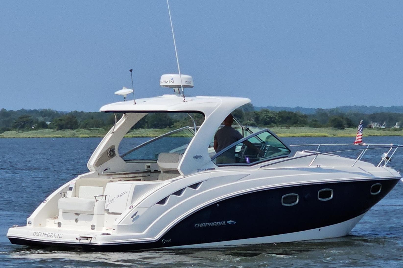 2015 Chaparral 310 Signature boat cruising on a calm lake with scenic background.