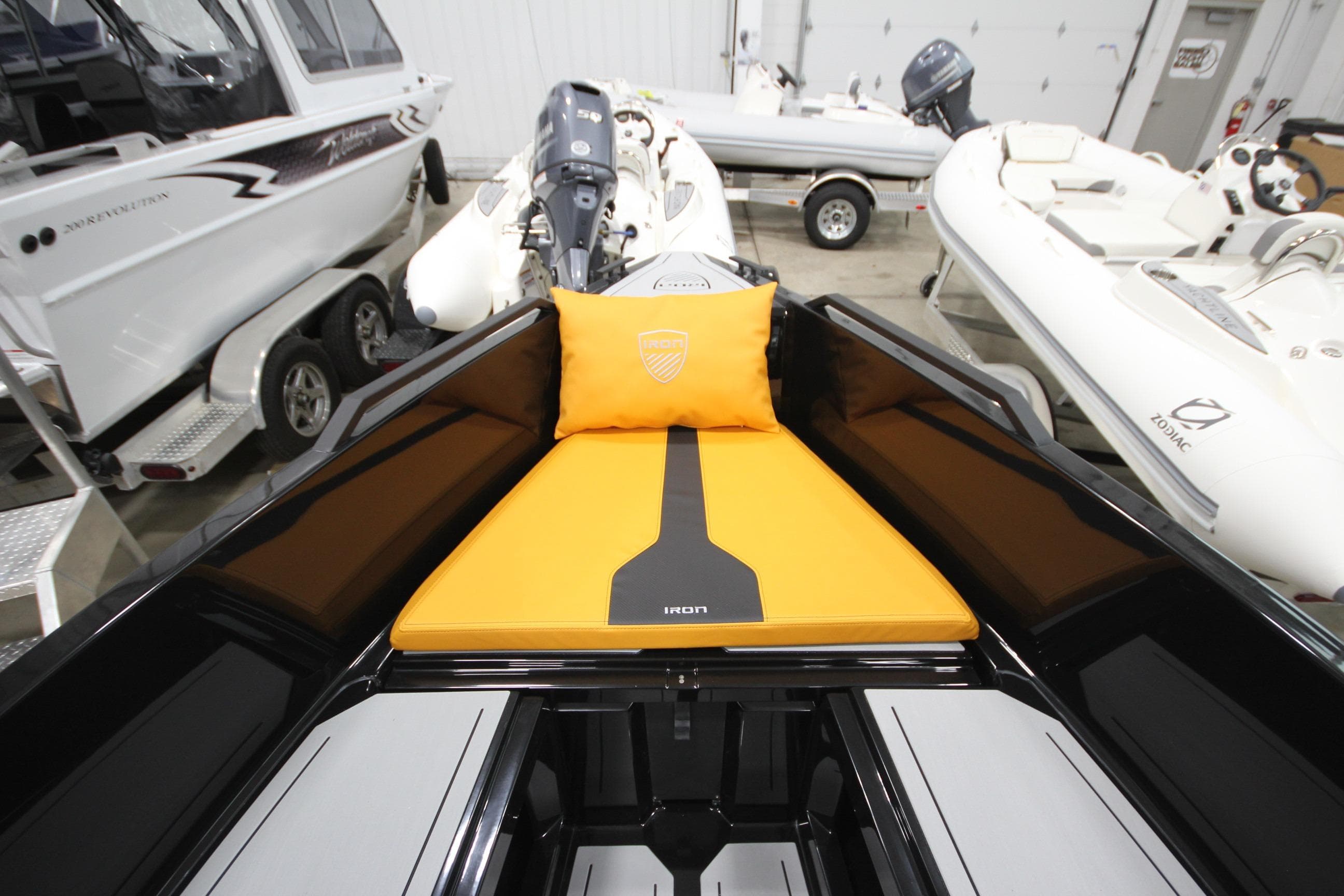 2026 Iron 767 T-top boat interior with orange cushion, surrounded by other boats in showroom.