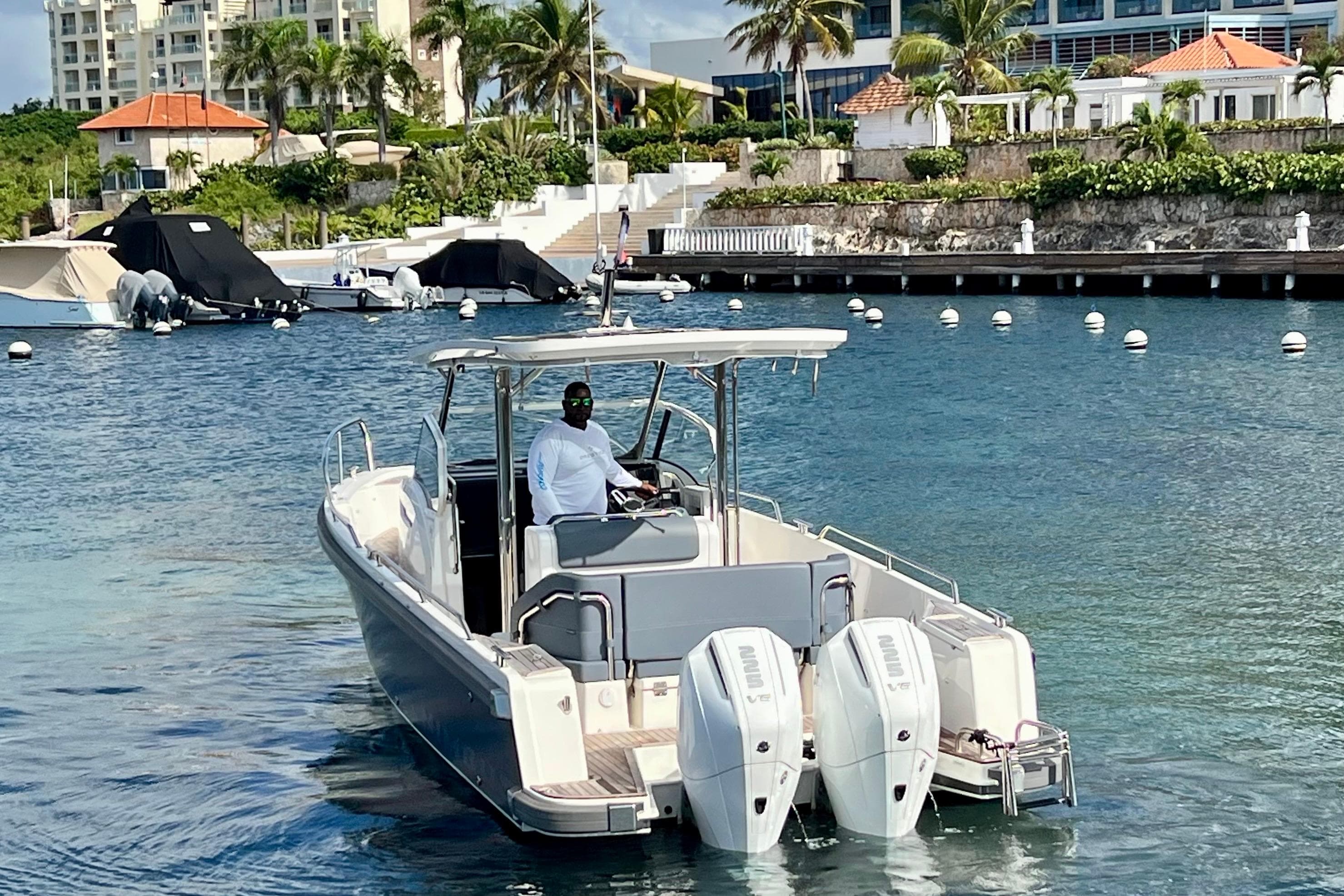 2025 Nimbus Tender 9 boat cruising in a scenic marina with palm trees and buildings.
