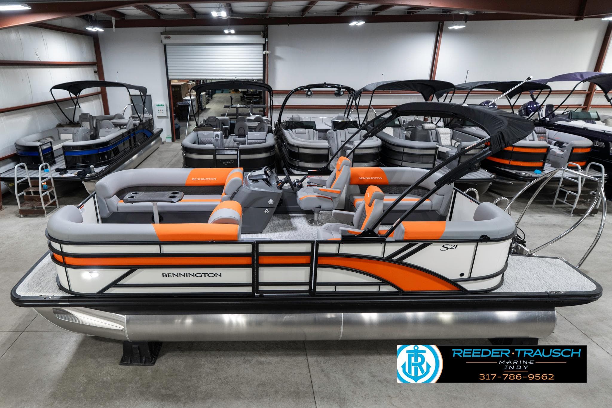 2025 Bennington 21 SSR pontoon boat with orange accents in a showroom.
