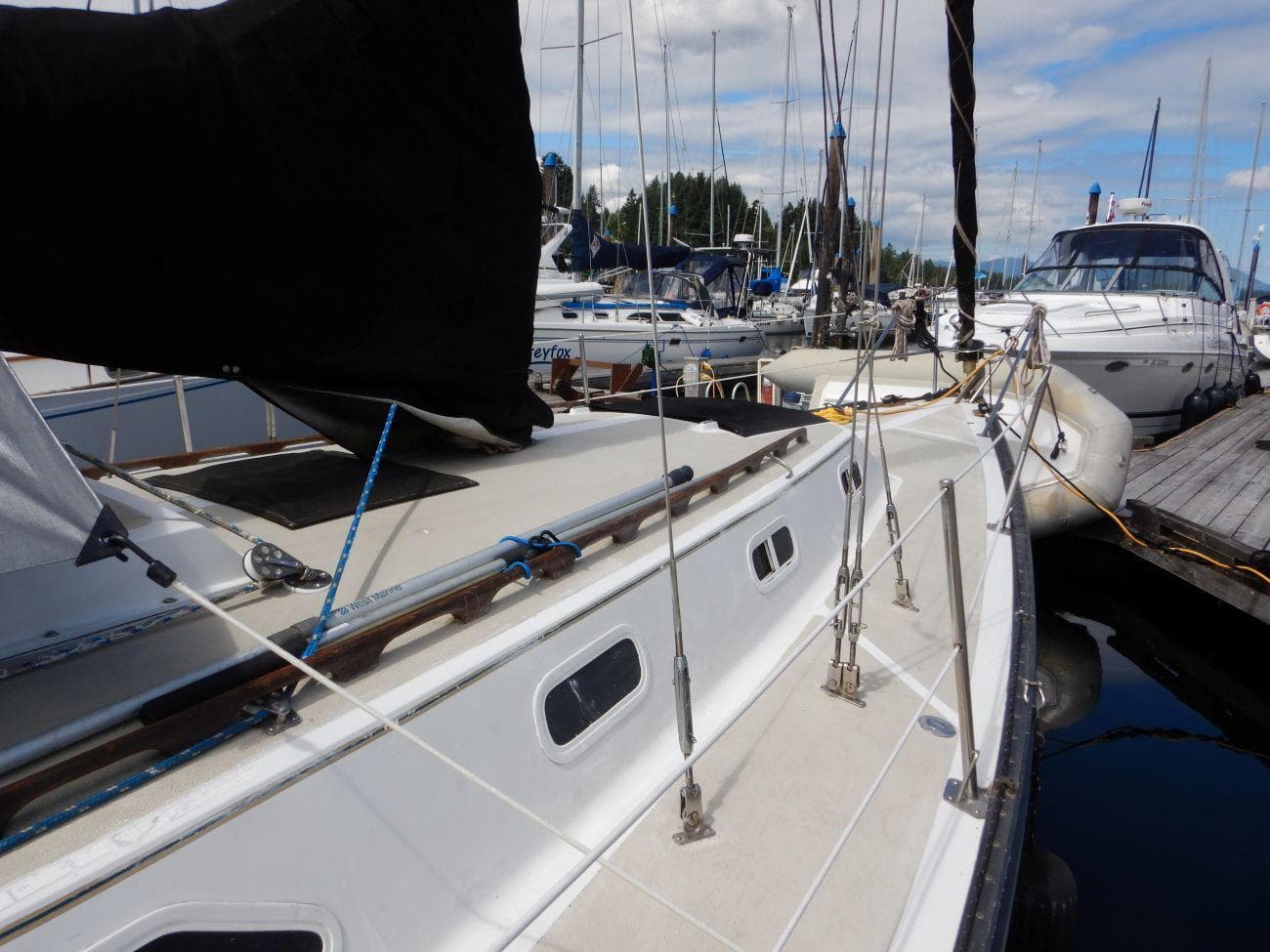 1978 Islander Sloop docked at marina, surrounded by other boats under a partly cloudy sky.
