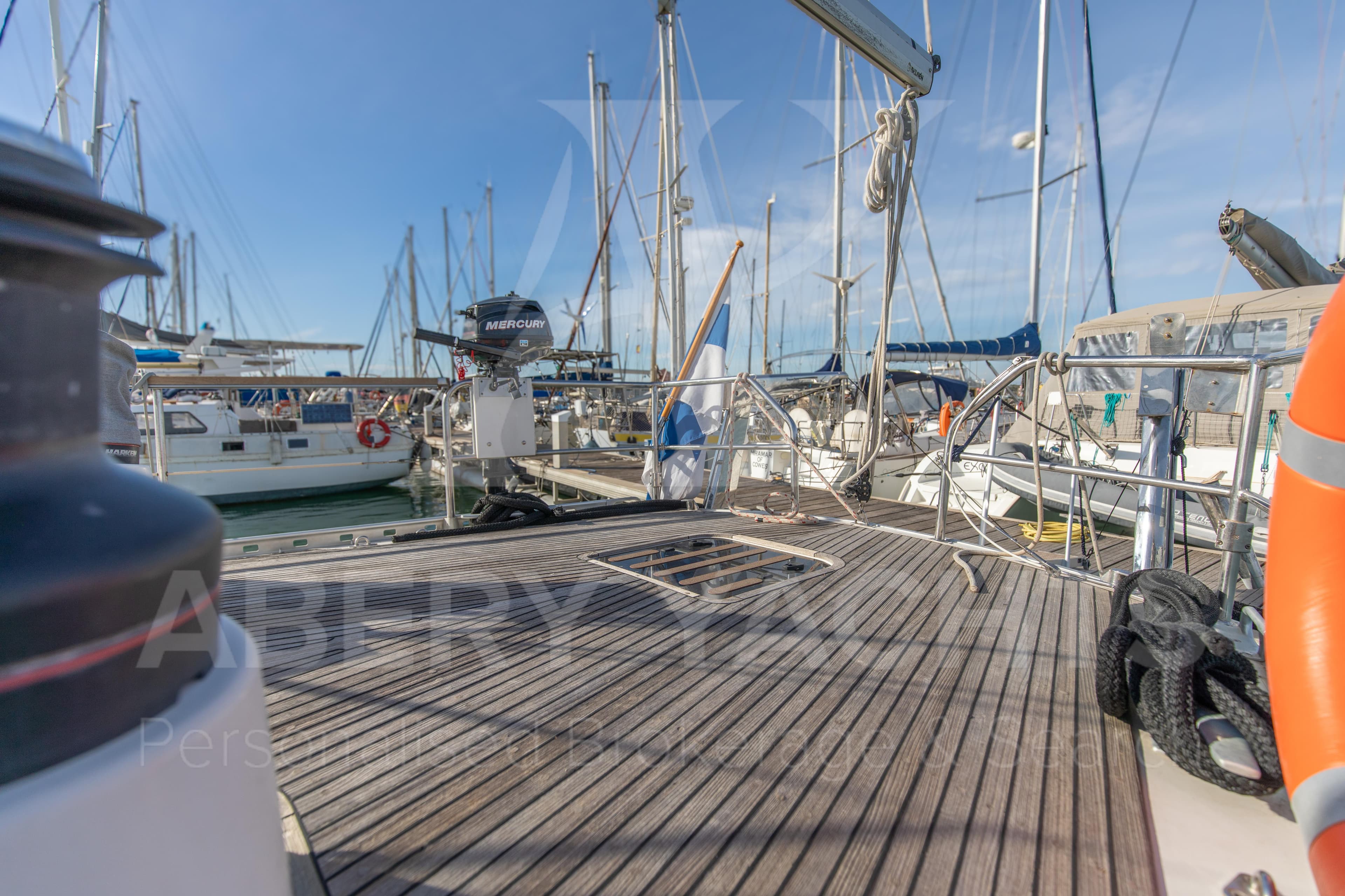Deck view of 2010 Nauticat 525 sailboat in marina, showcasing wooden flooring and rigging.