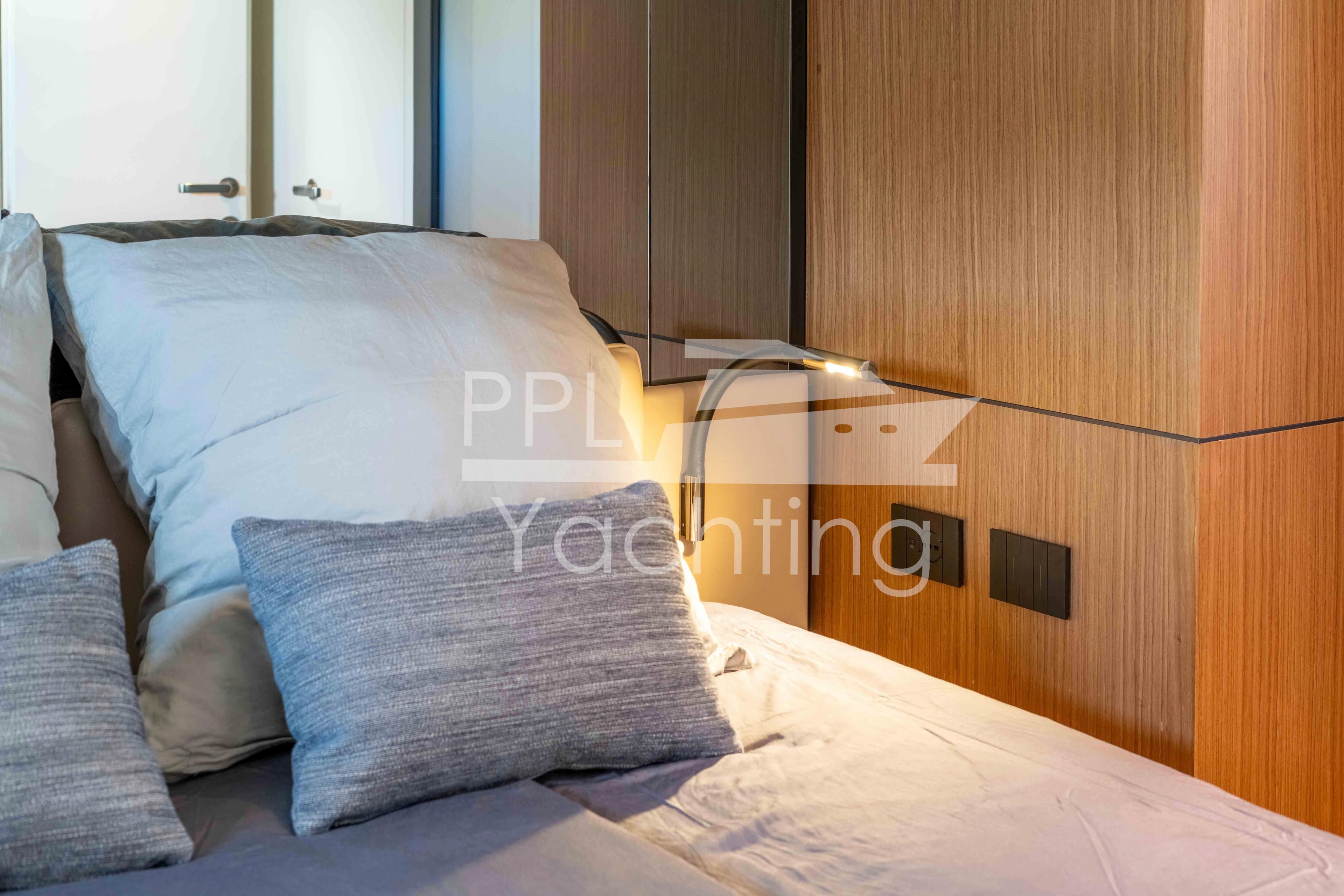 Luxurious cabin interior of 2024 Bluegame BGX63 yacht with plush bedding and modern wood paneling.