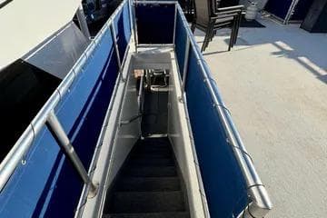 Staircase on 2013 Bravada Bella Luna boat with blue railings and outdoor seating.