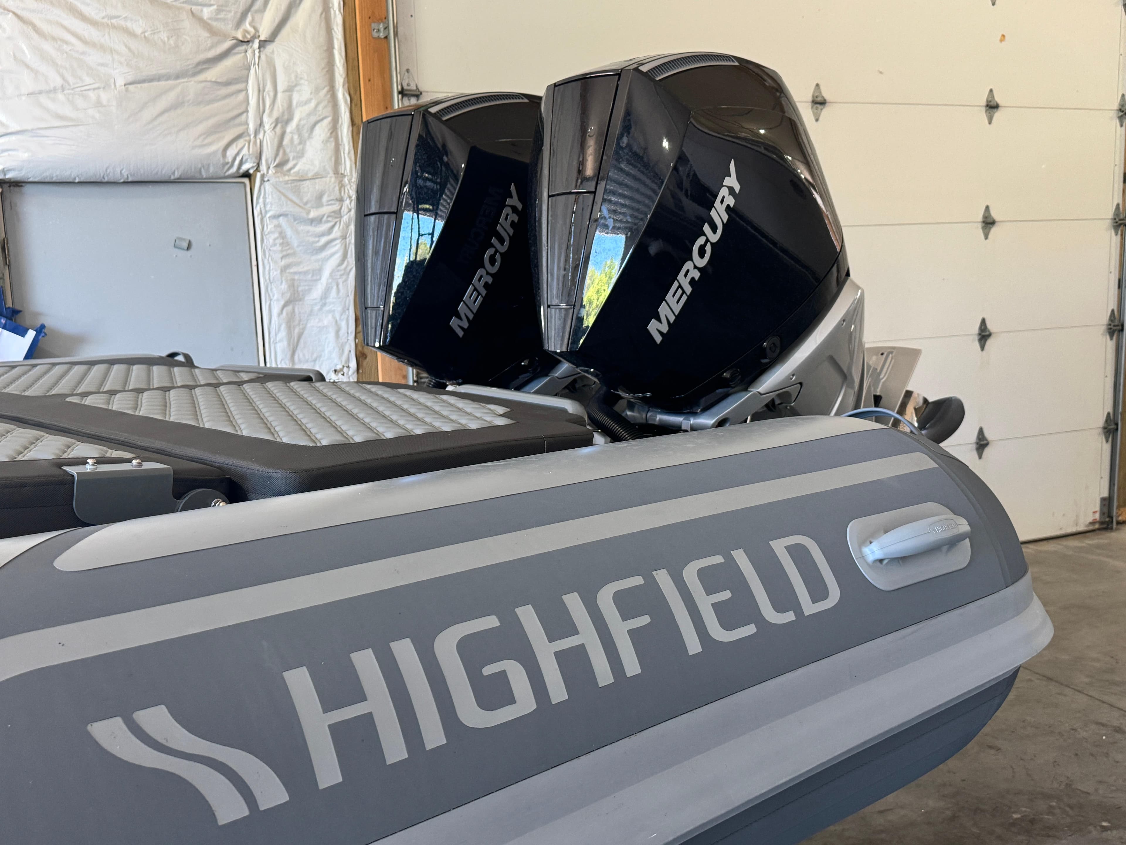 2024 Highfield Sport 900 boat with dual Mercury outboard engines in a garage.