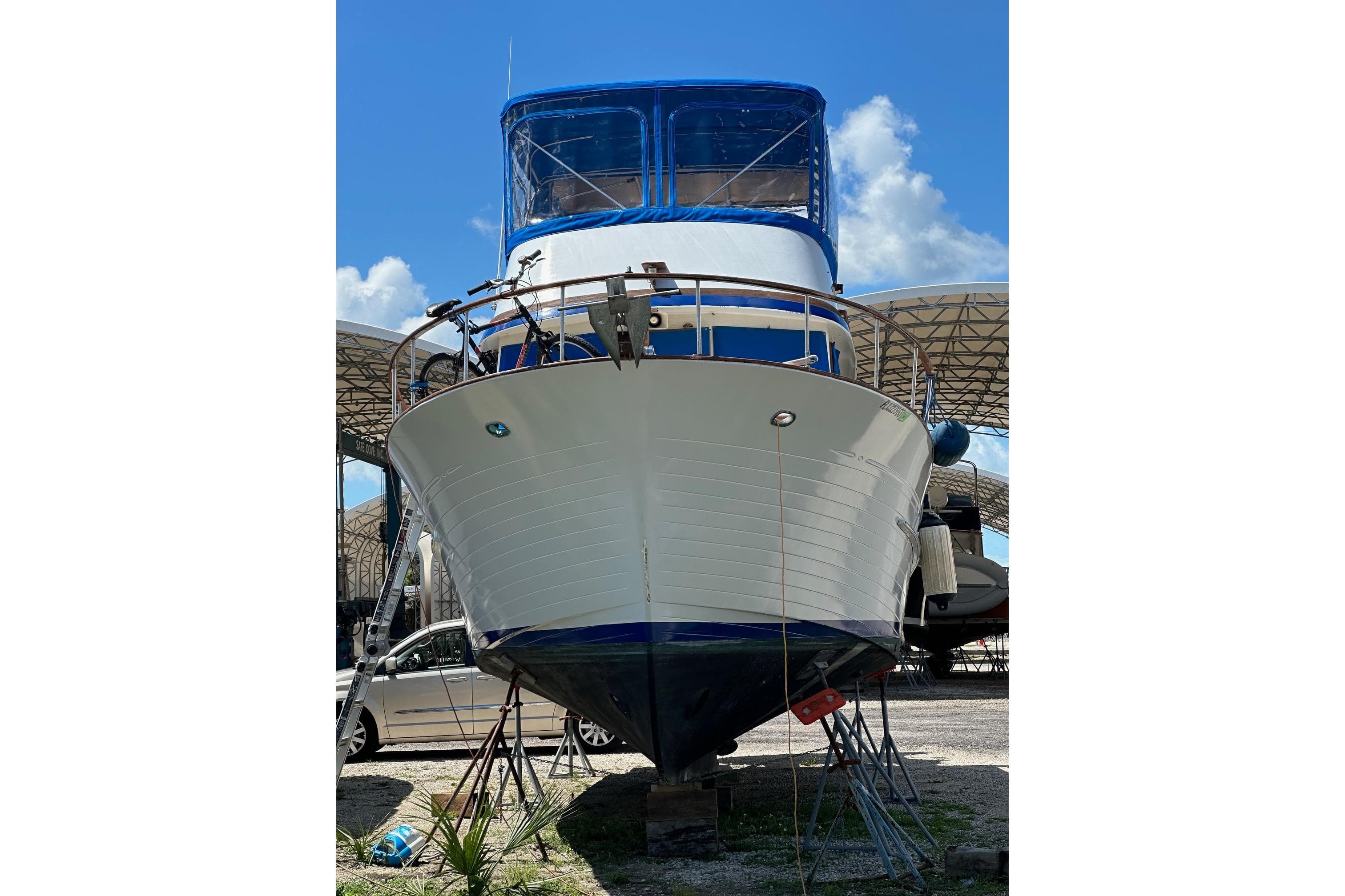 1981 Albin 36 Trawler on dry dock, blue canopy, sunny day.