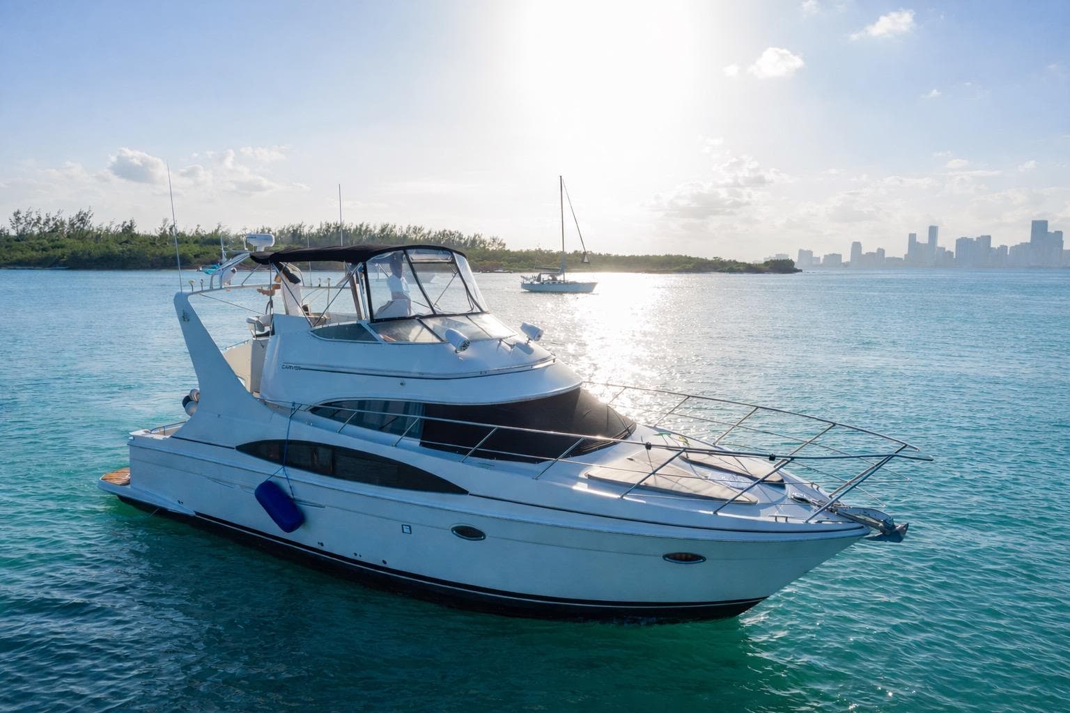 2004 Carver 420 Mariner yacht on serene blue waters with city skyline in background.