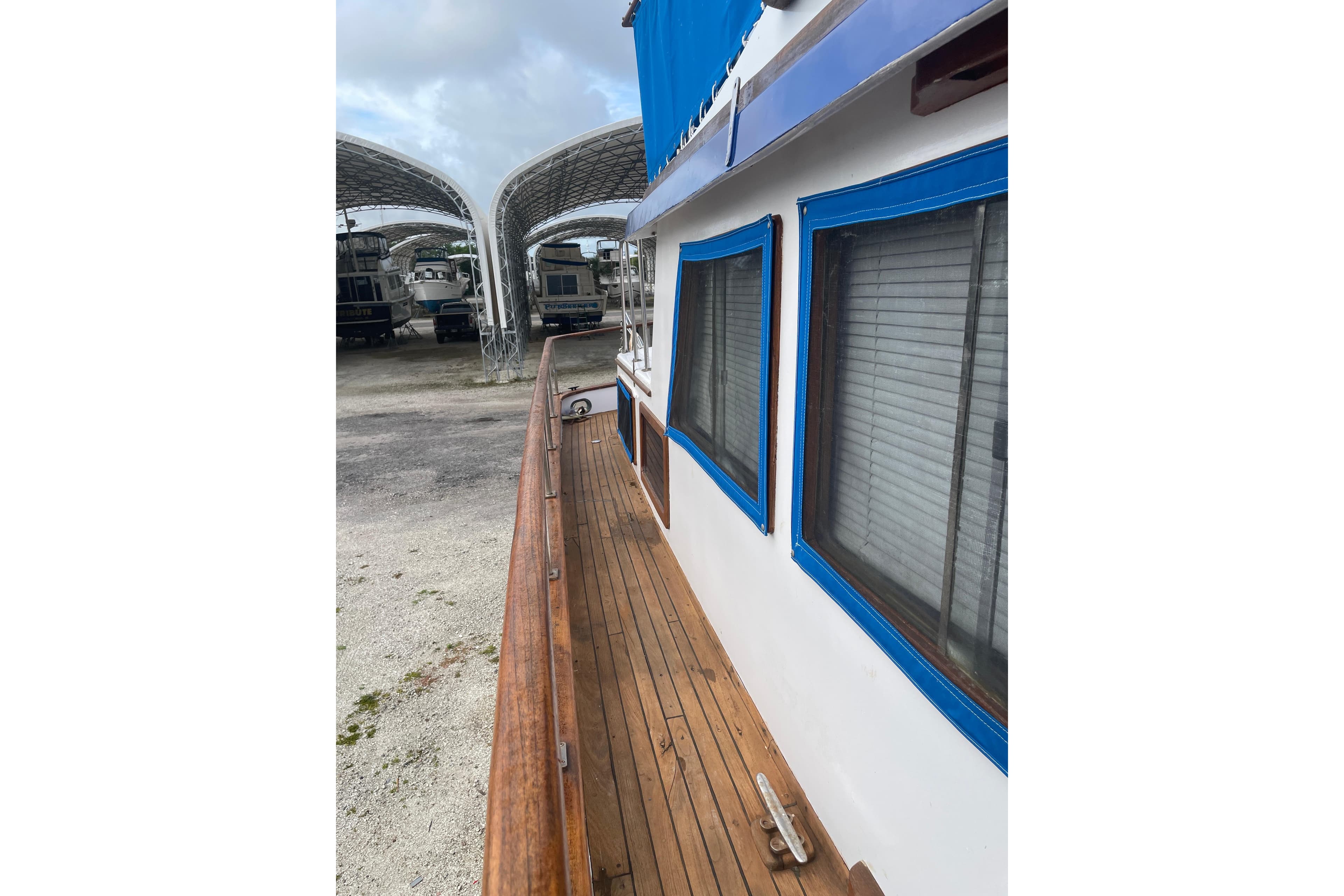 1981 Albin 36 Trawler with wooden deck and blue-trimmed windows in a boatyard.