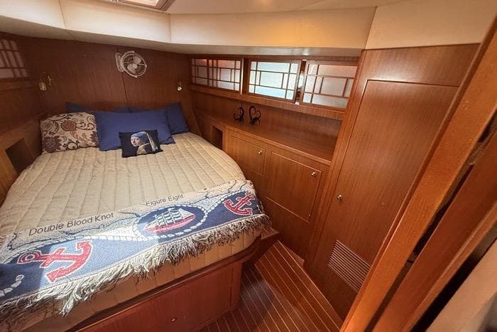 Luxurious 2007 Island Pilot 395 cabin with cozy bed and elegant wood finish.