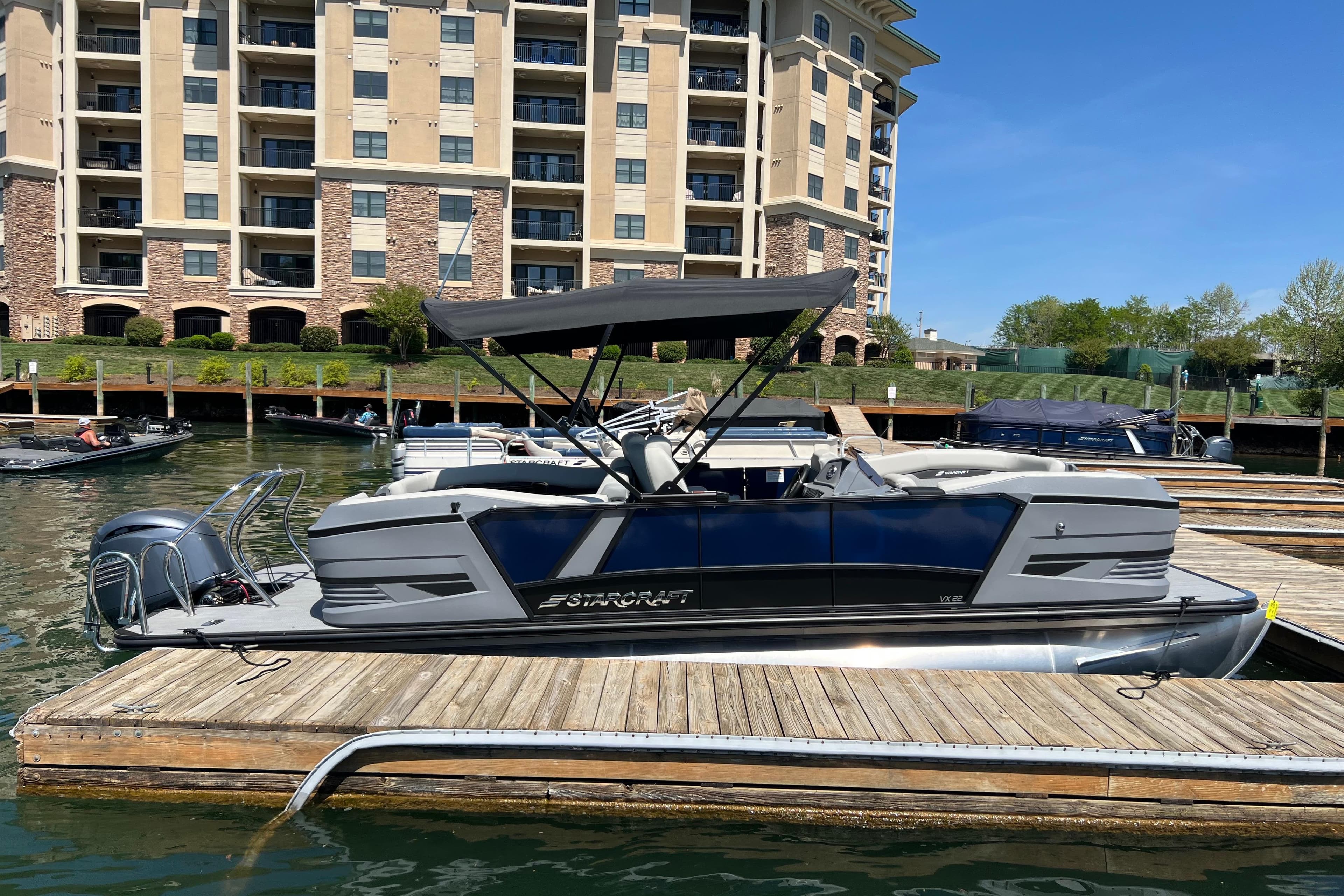 2026 Starcraft VX 22 R DH pontoon boat docked by waterfront apartments.