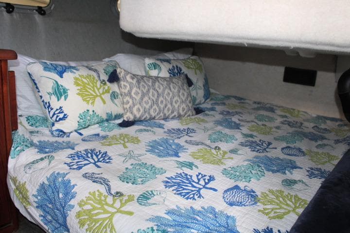 Cozy bedroom in 1992 Bayliner 3288 Motoryacht with ocean-themed bedding.