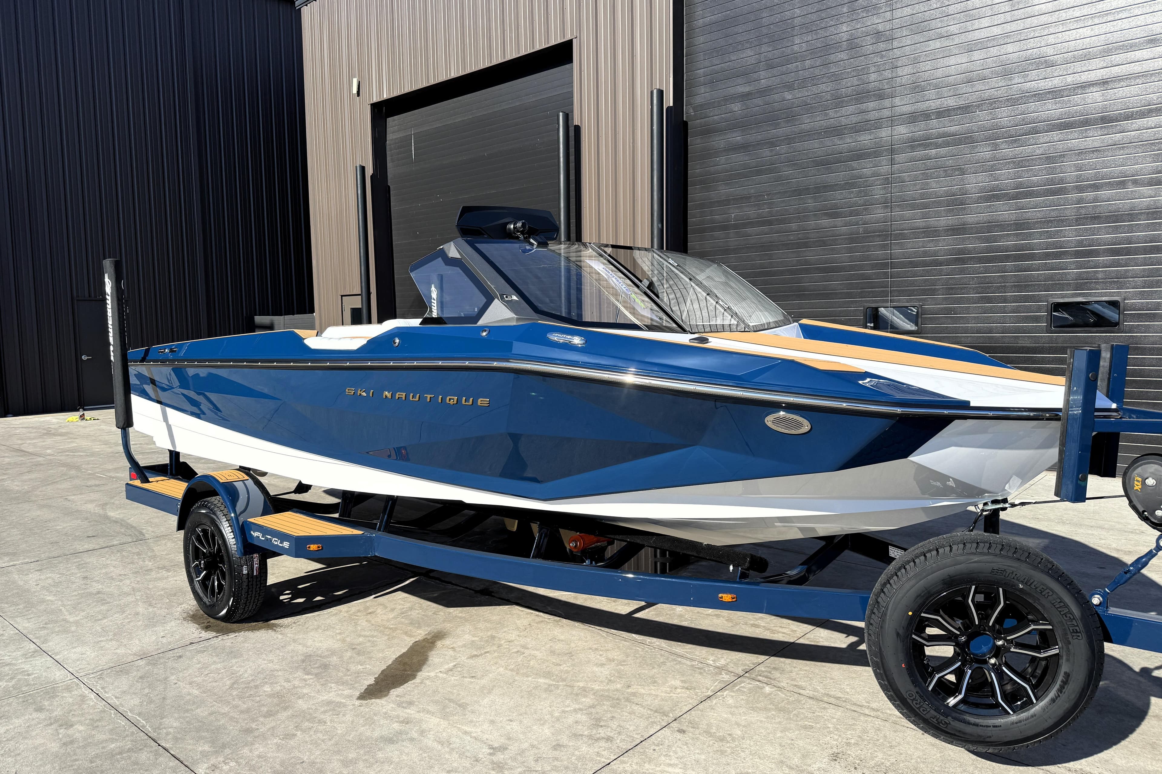 2026 Nautique Ski Nautique boat on trailer, blue and white design, parked outdoors.