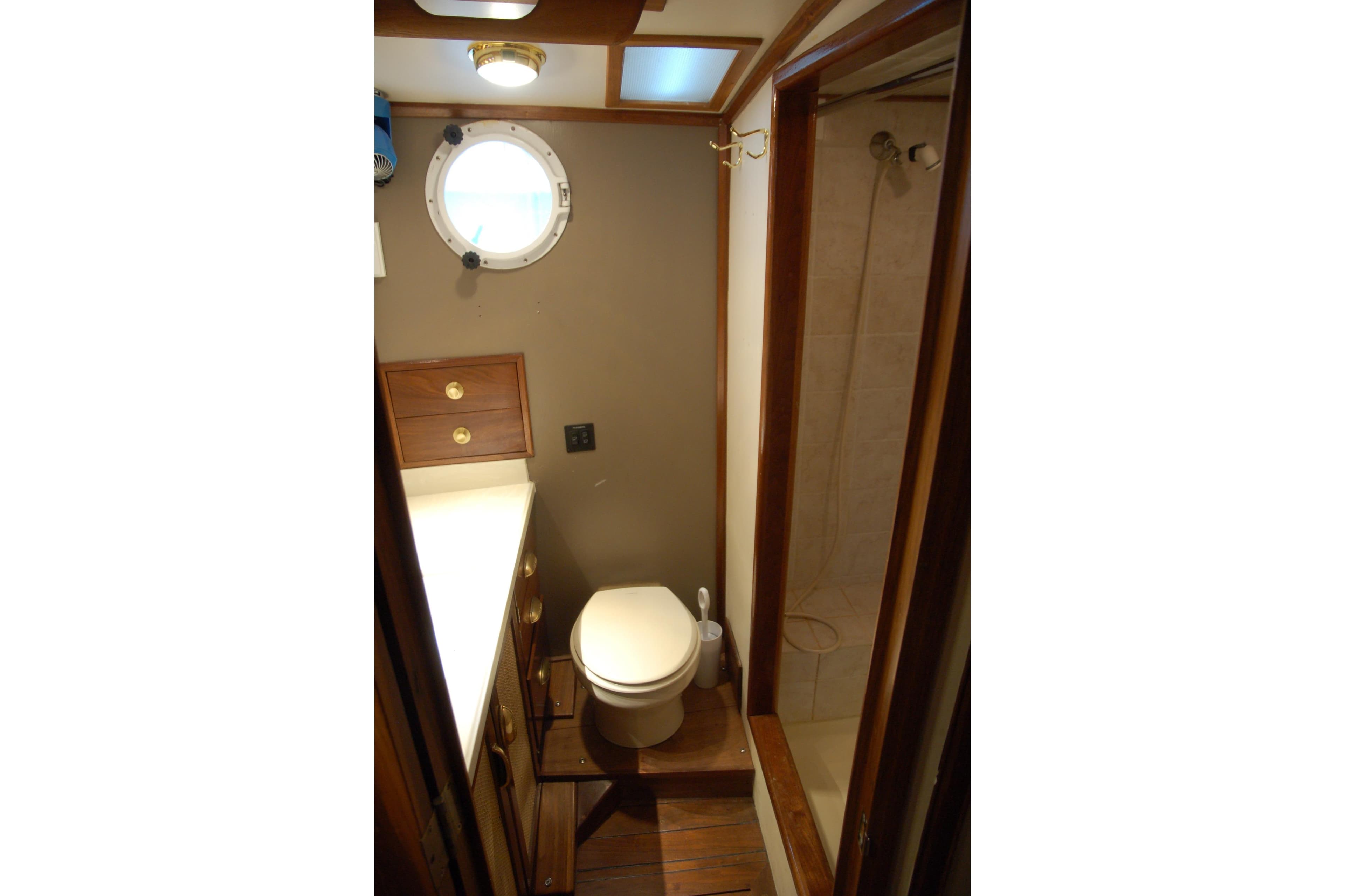 Compact boat bathroom with porthole, shower, and wooden cabinetry, Custom Sprague 2006 model.