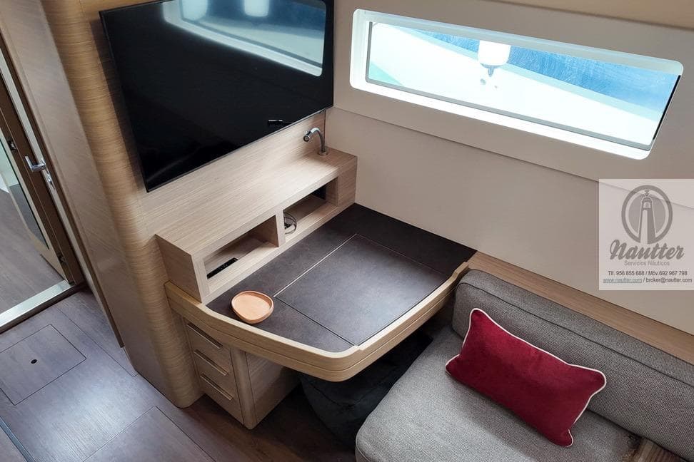 Interior of 2023 Lagoon 46 yacht with TV, desk, and sofa.