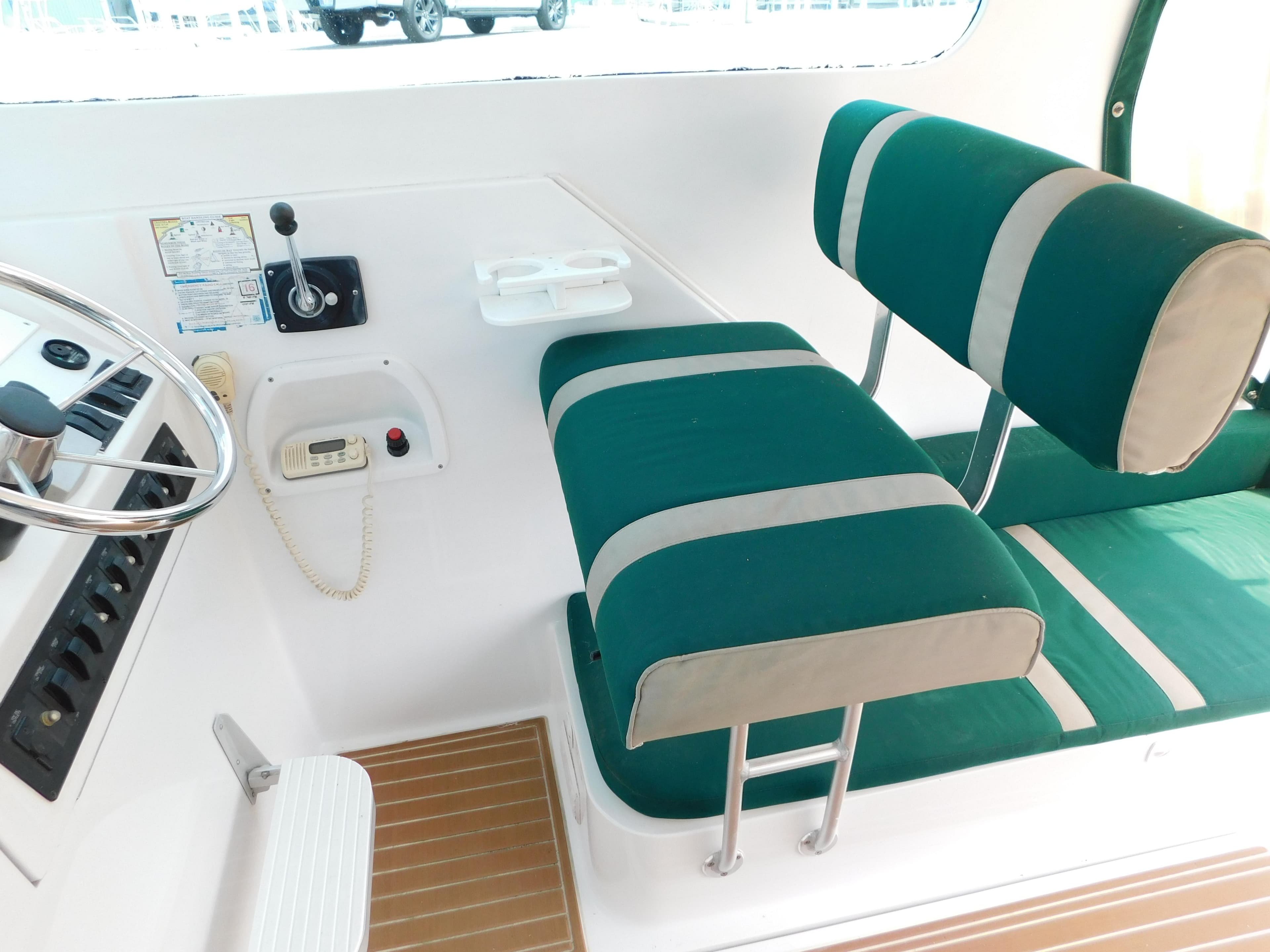 1999 Mainship Pilot 30 cockpit with green and white seating, steering wheel, and control panel.