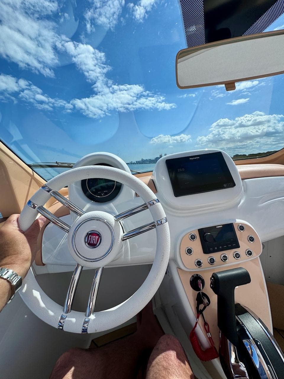 2024 Fiat 500 Car Offshore interior with steering wheel and dashboard, under a clear blue sky.