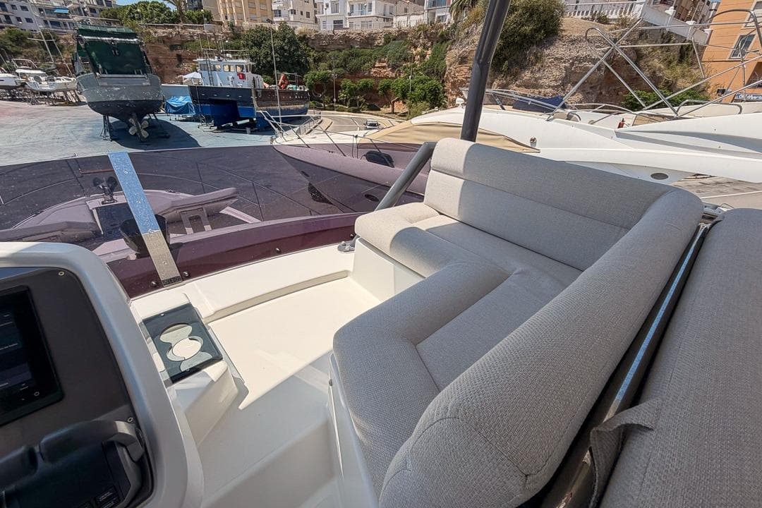 Luxurious seating area on 2022 Beneteau Monte Carlo 52 yacht, docked at marina.