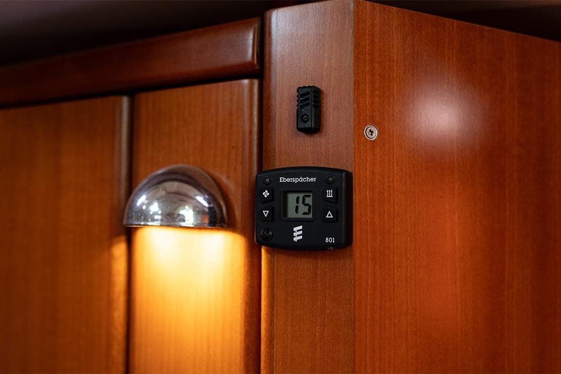 Thermostat and light on wooden panel of 2006 Dufour 385 yacht interior.