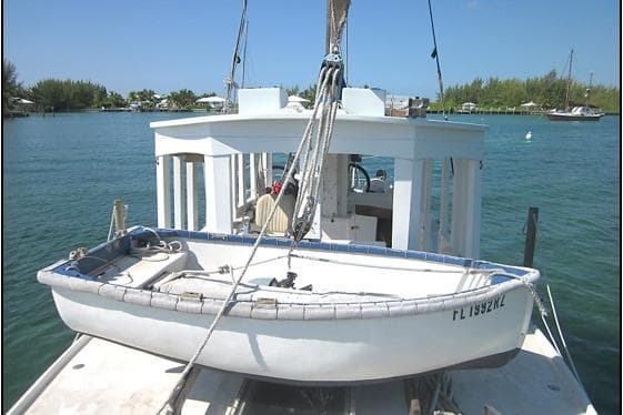 Custom 2005 sail-assisted trawler with dinghy on deck, moored in a serene harbor.